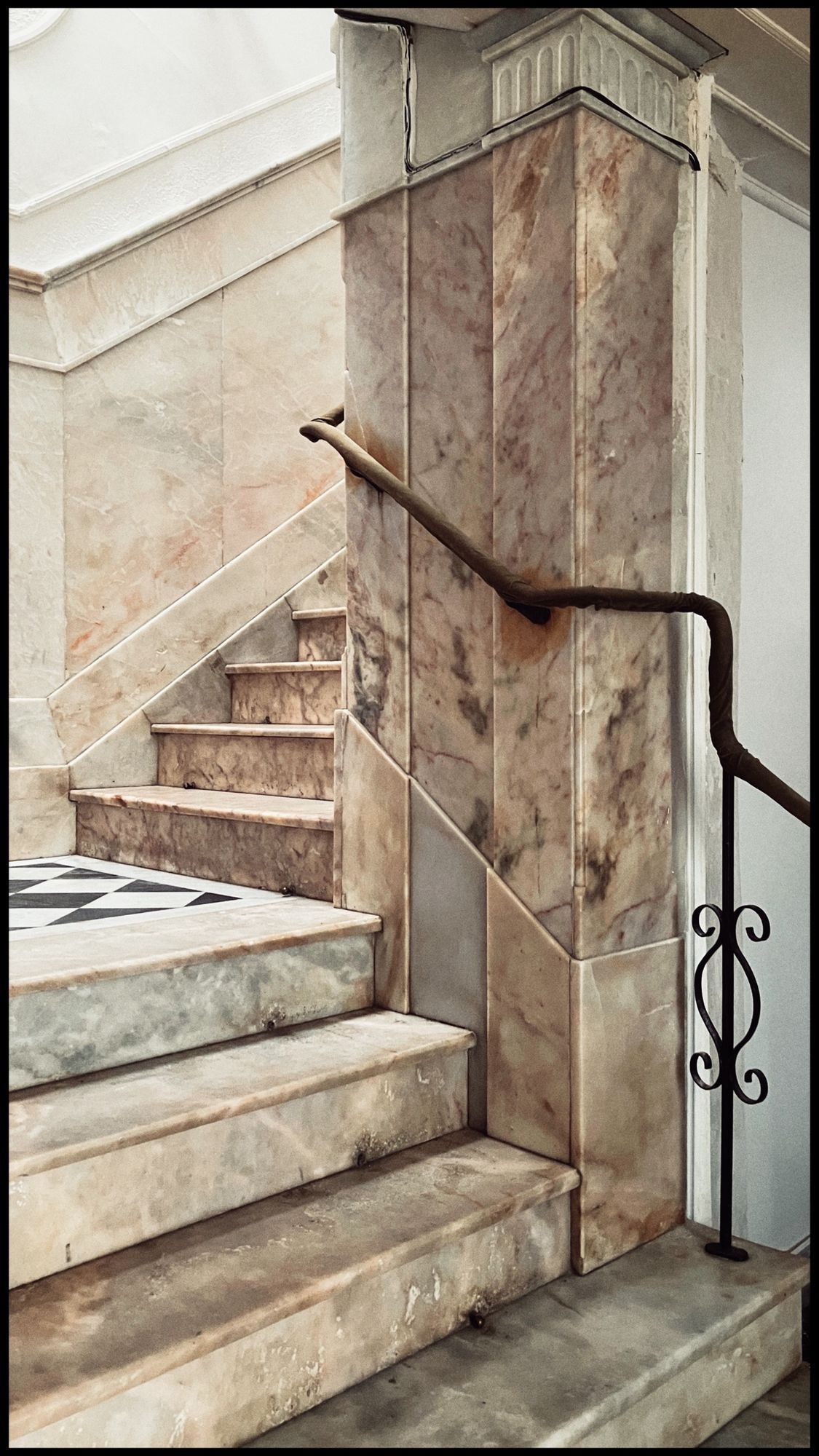 Impressive marble stairs, pillar and wrought iron handrail.