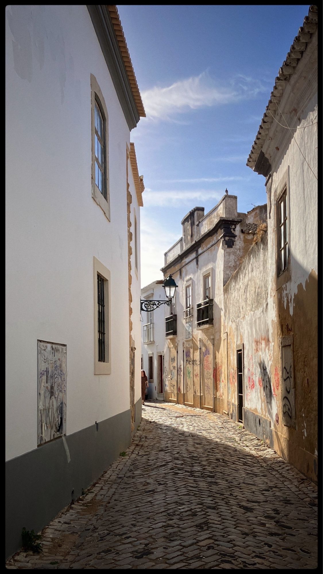 Winding cobbled street with afternoon sun illuminating old buildings.