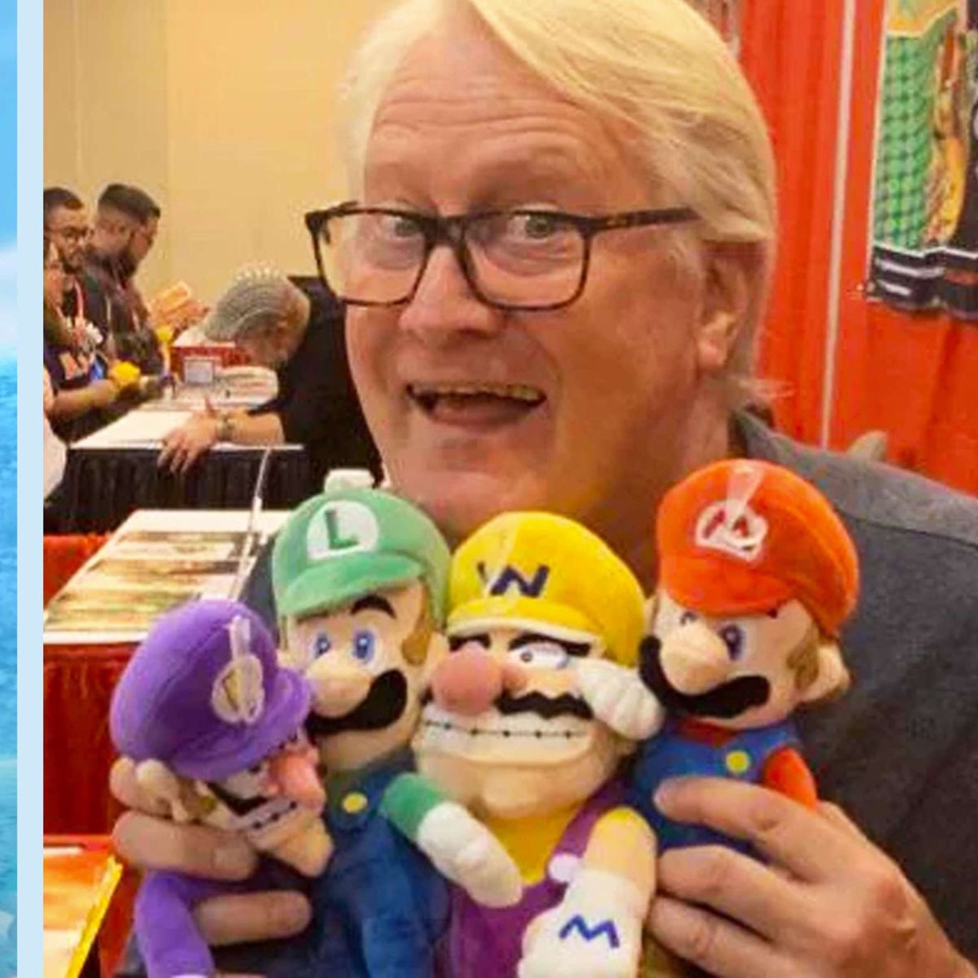 Charles Martinet hält Plüschfiguren der bekannten Super Mario Brüder in der Hand.