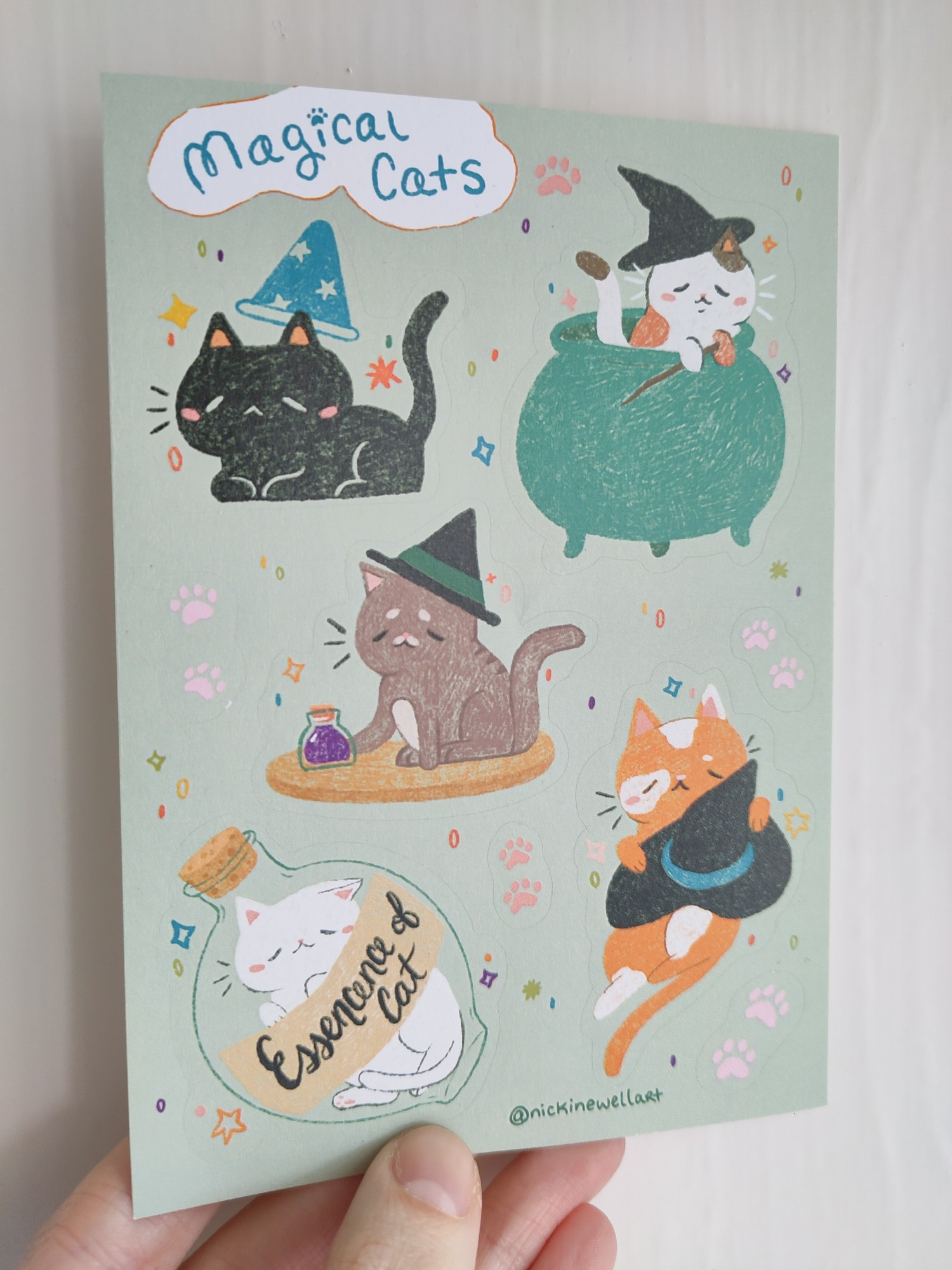 A picture of an A6 magical cat themed sticker sheet. The sticker sheet contains 5 cat stickers and some small paw print stickers.