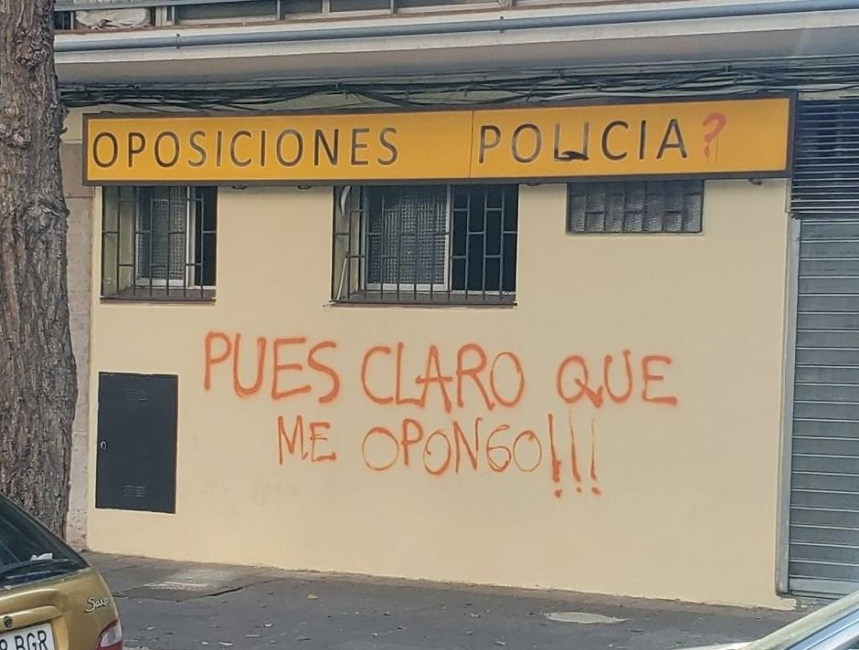 Imagen de local donde se imparten clases para oposiciones a policía y una pintada en la pared que dice: PUES CLARO QUE ME OPONGO!!!