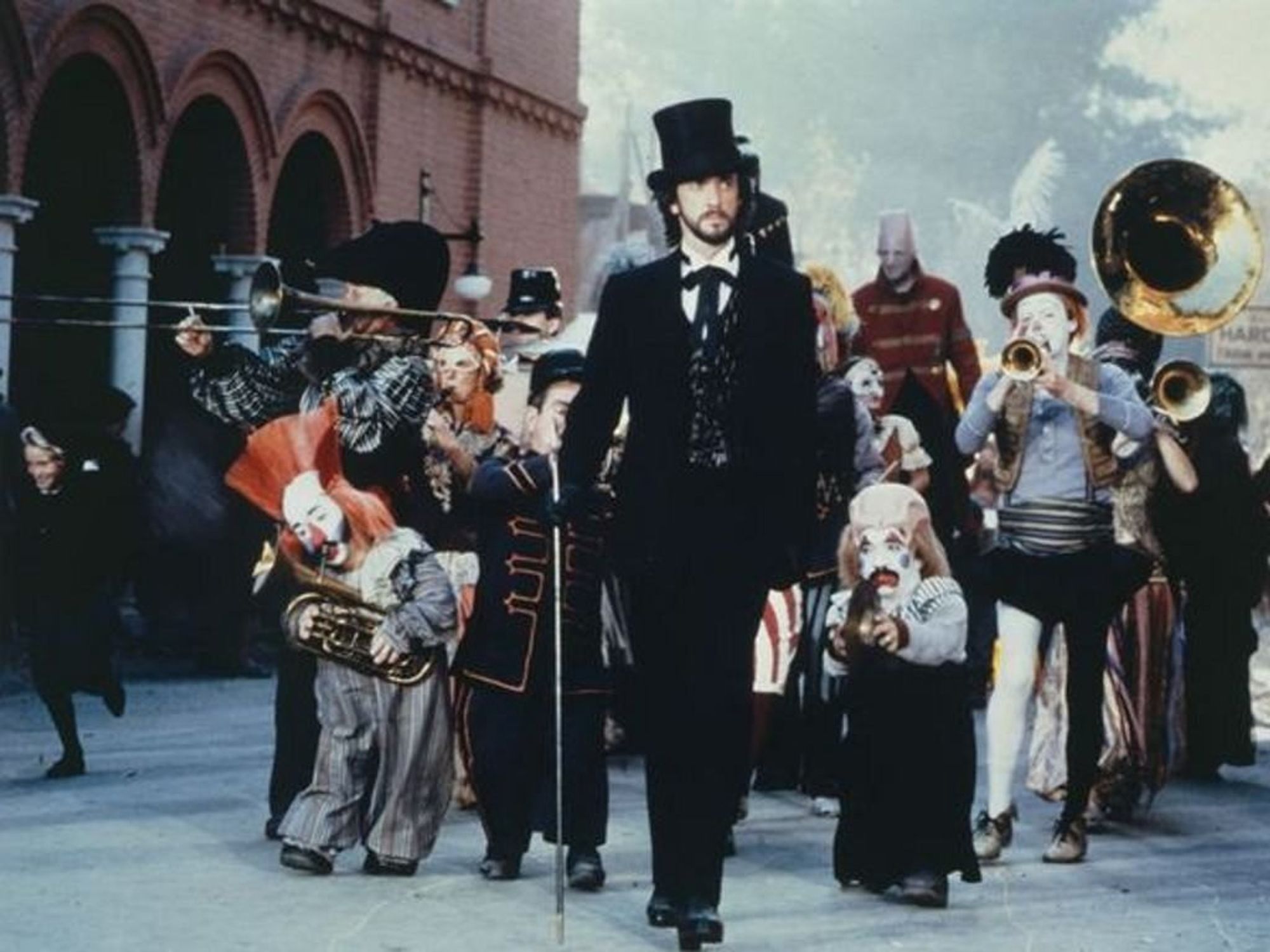 a 30-something Jonathan Pryce, wearing a suit and top hat, holding a cane, and leading a parade of clowns playing brass instruments. he looks like a sexy magician, which unfortunately for me is one of my types