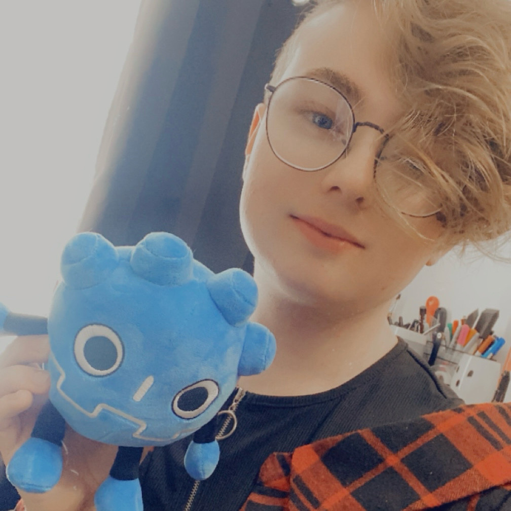 Joe holding up a Godot plush looking very cute in a black red over shoulder crop top.