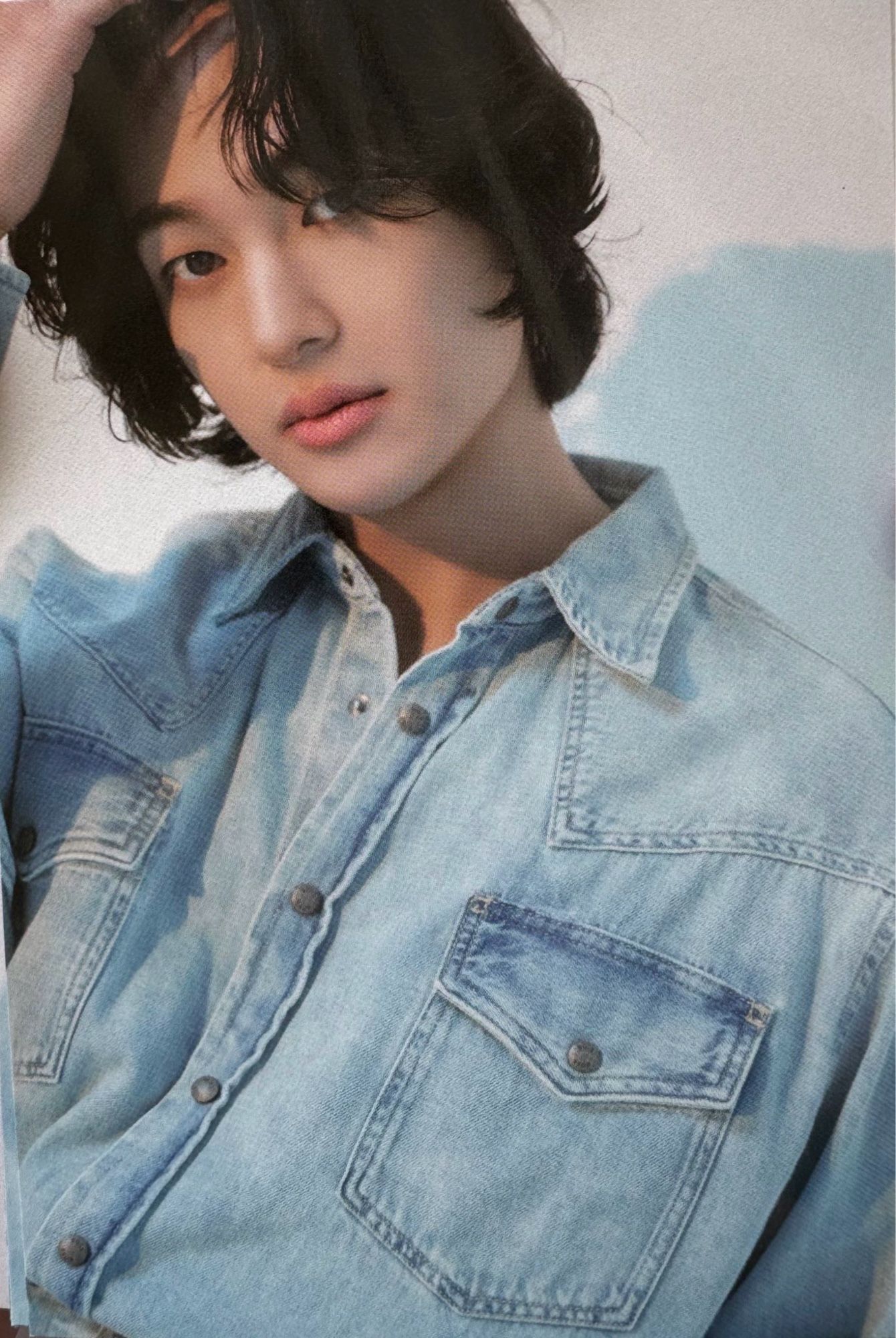 SHINee Onew, with longer black hair, wearing a denim top.