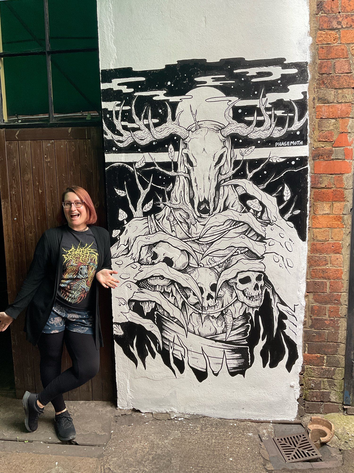 A photo of myself standing next to a mural I painted in POSCA paint pens for the Cheltenham Paint Festival in July. The piece depicts a Leshy.