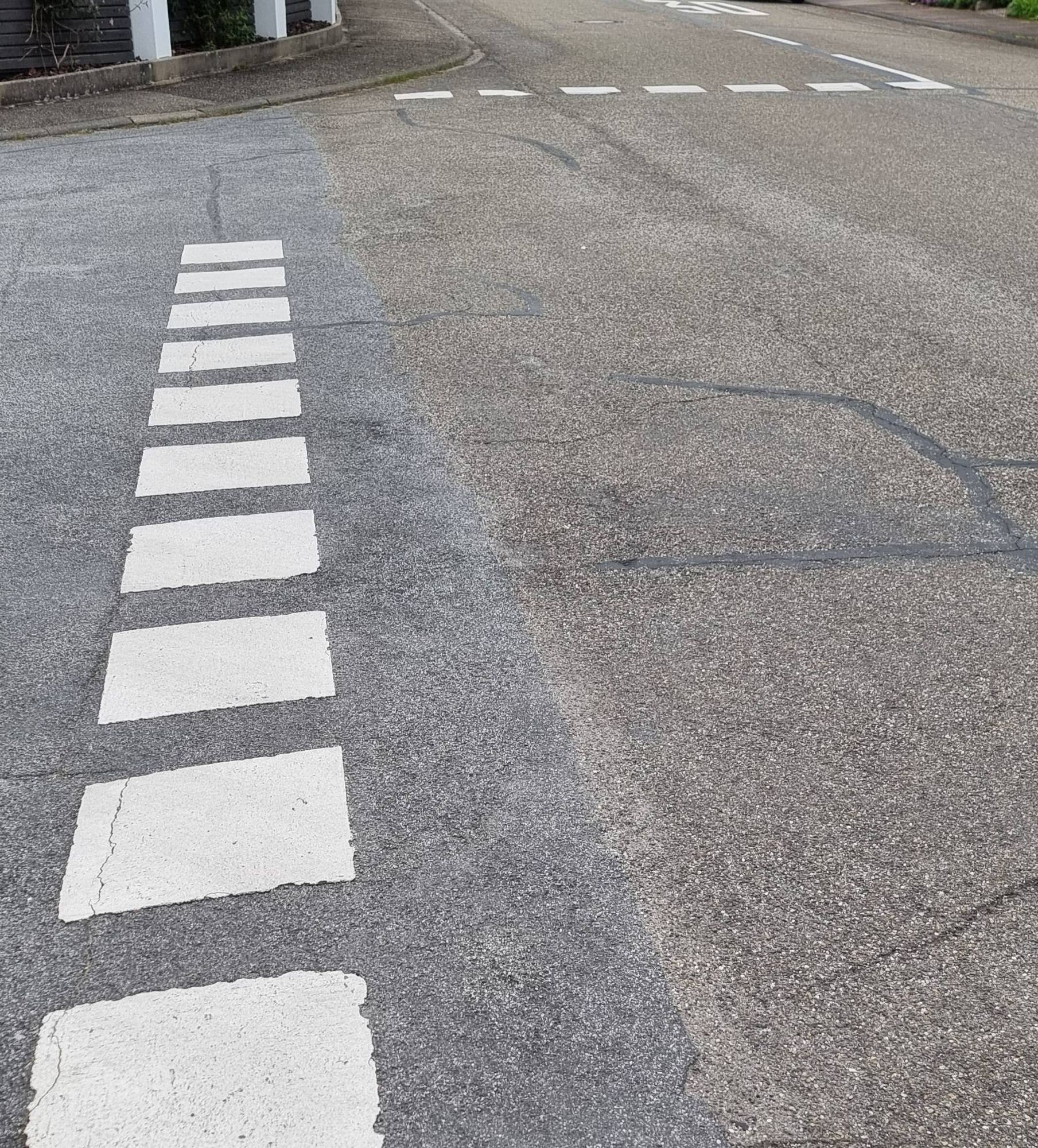 Die weißen, gestrichelten Haltelinien an einer Straßeneinmündung, bei der rechts vor links gilt.