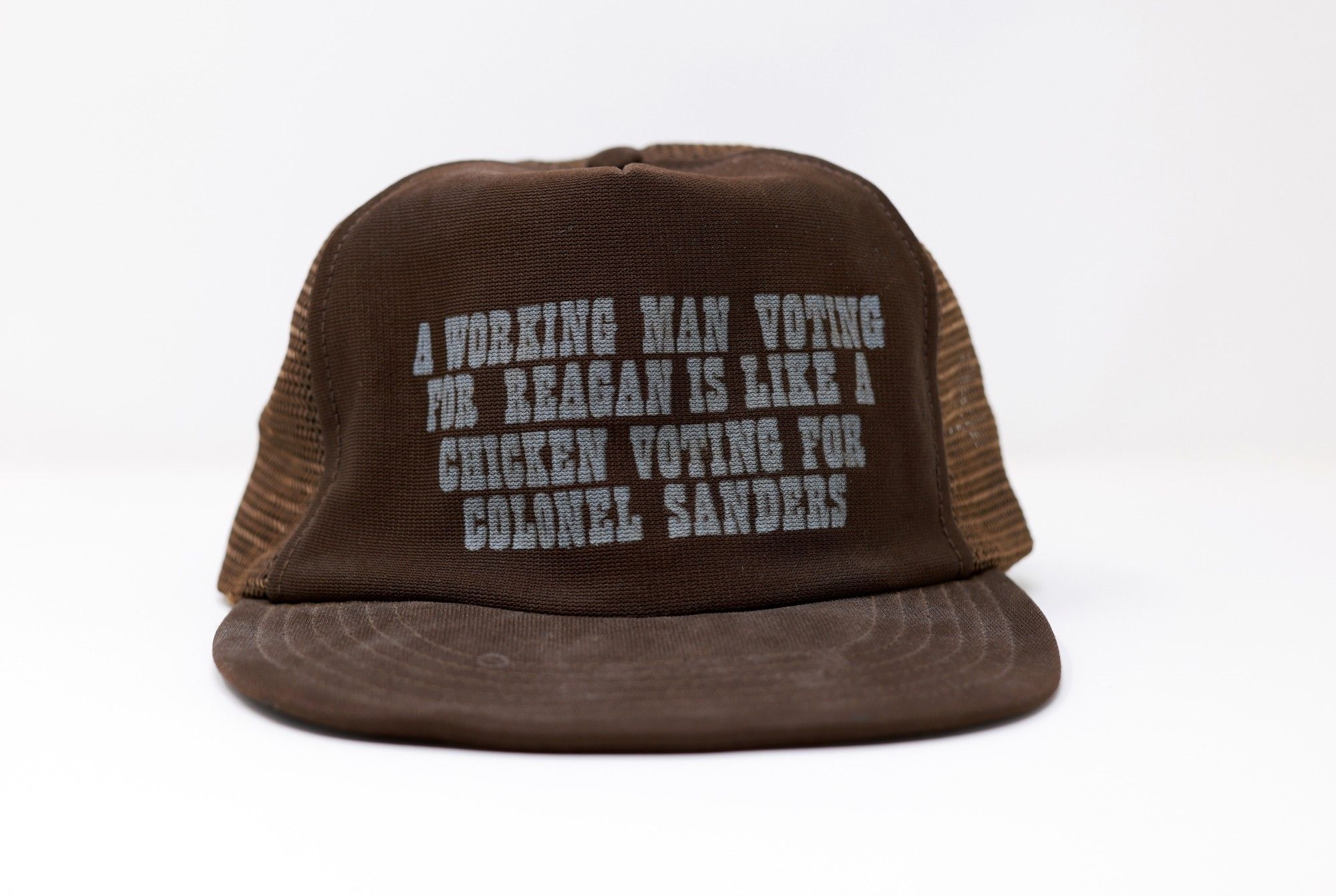 brown ball cap with white text that reads "a working man voting for Reagan is like a chicken voting for Colonel Sanders"