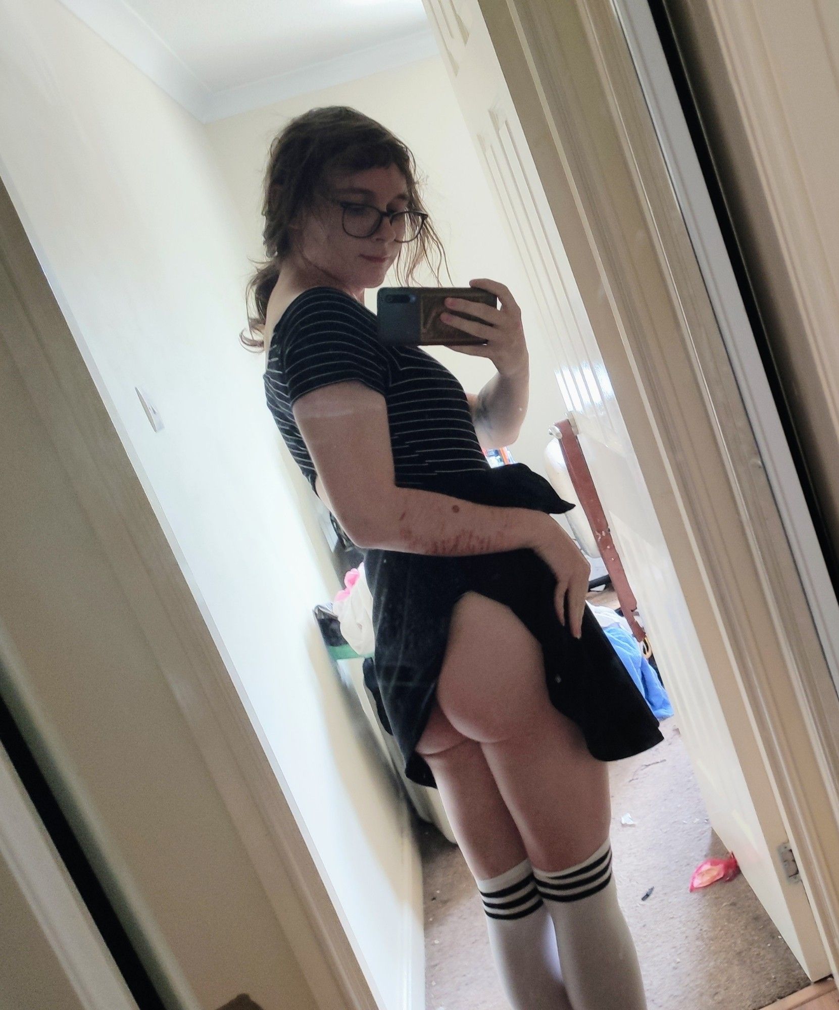 photo of me in white socks, a black skirt and a black and white stripey body suit. i'm lifting the skirt to reveal my big round ass