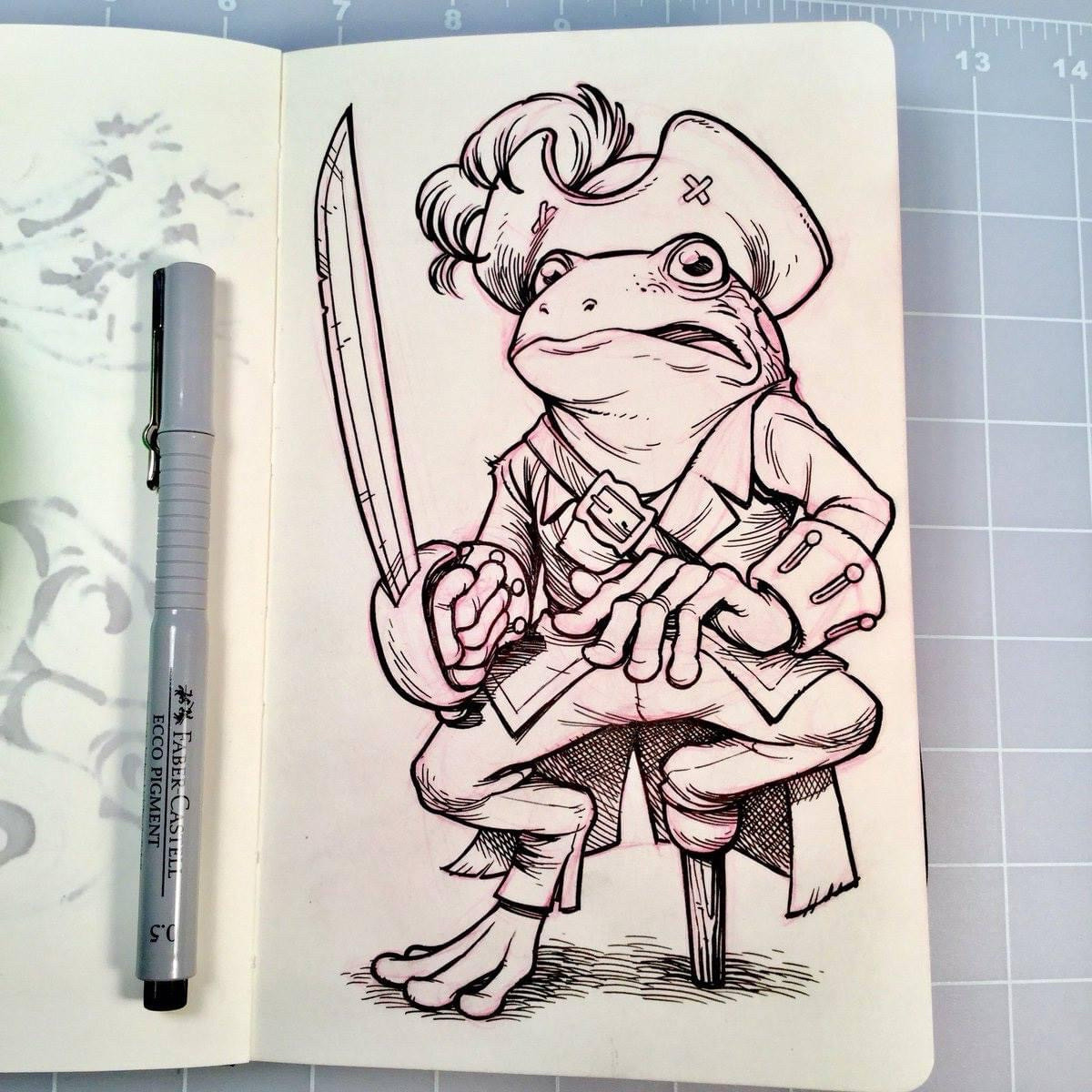 A black and white pen and ink drawing of an anthropomorphic frog pirate in a small Moleskine sketchbook.