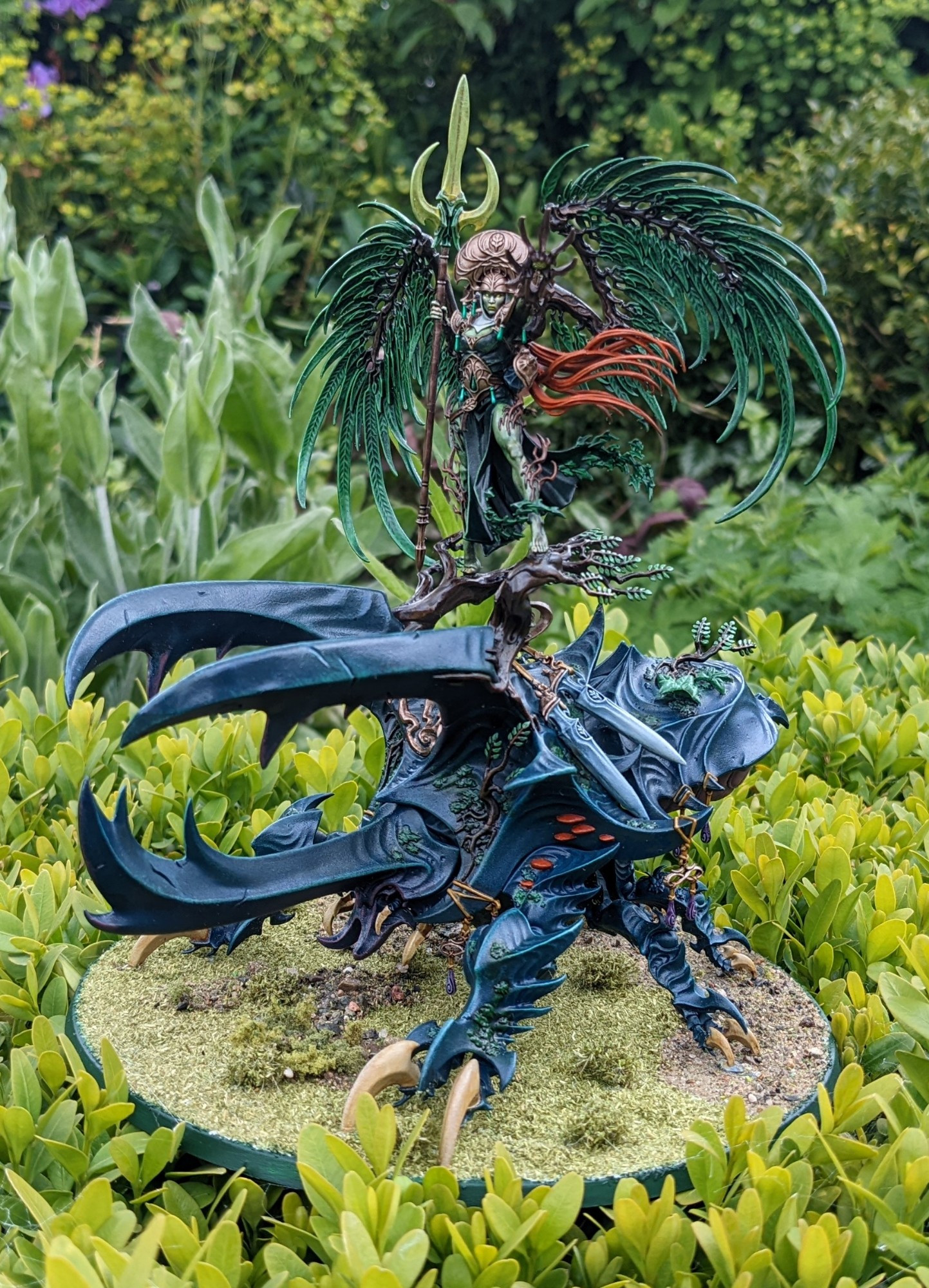 A painted Alarielle model from Age of Sigmar sitting among some greenery 