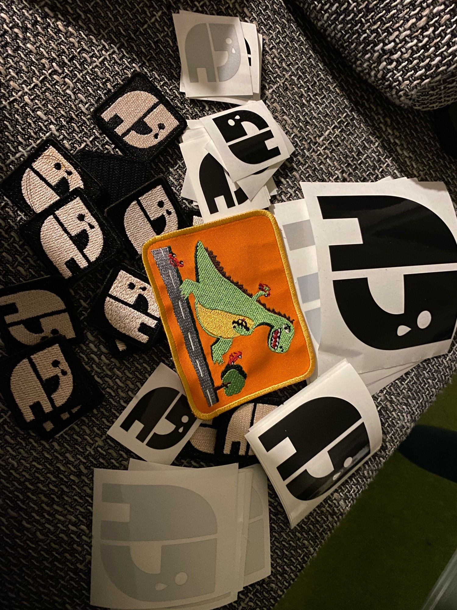 Patches und Sticker #RIPNatenom und ein Patch mit einem eskalierenden Dino