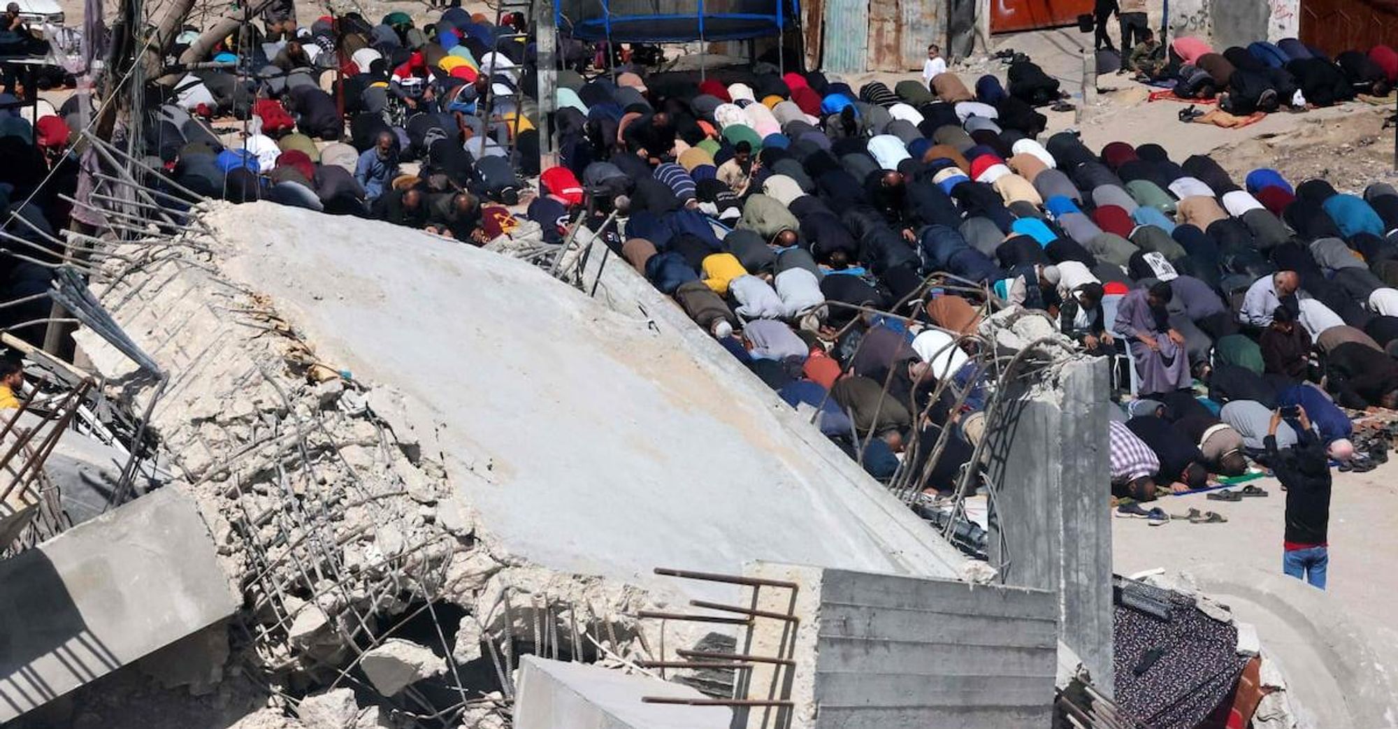 Gazans praying in the rubble of a mosque destroyed by Apartheid Israel