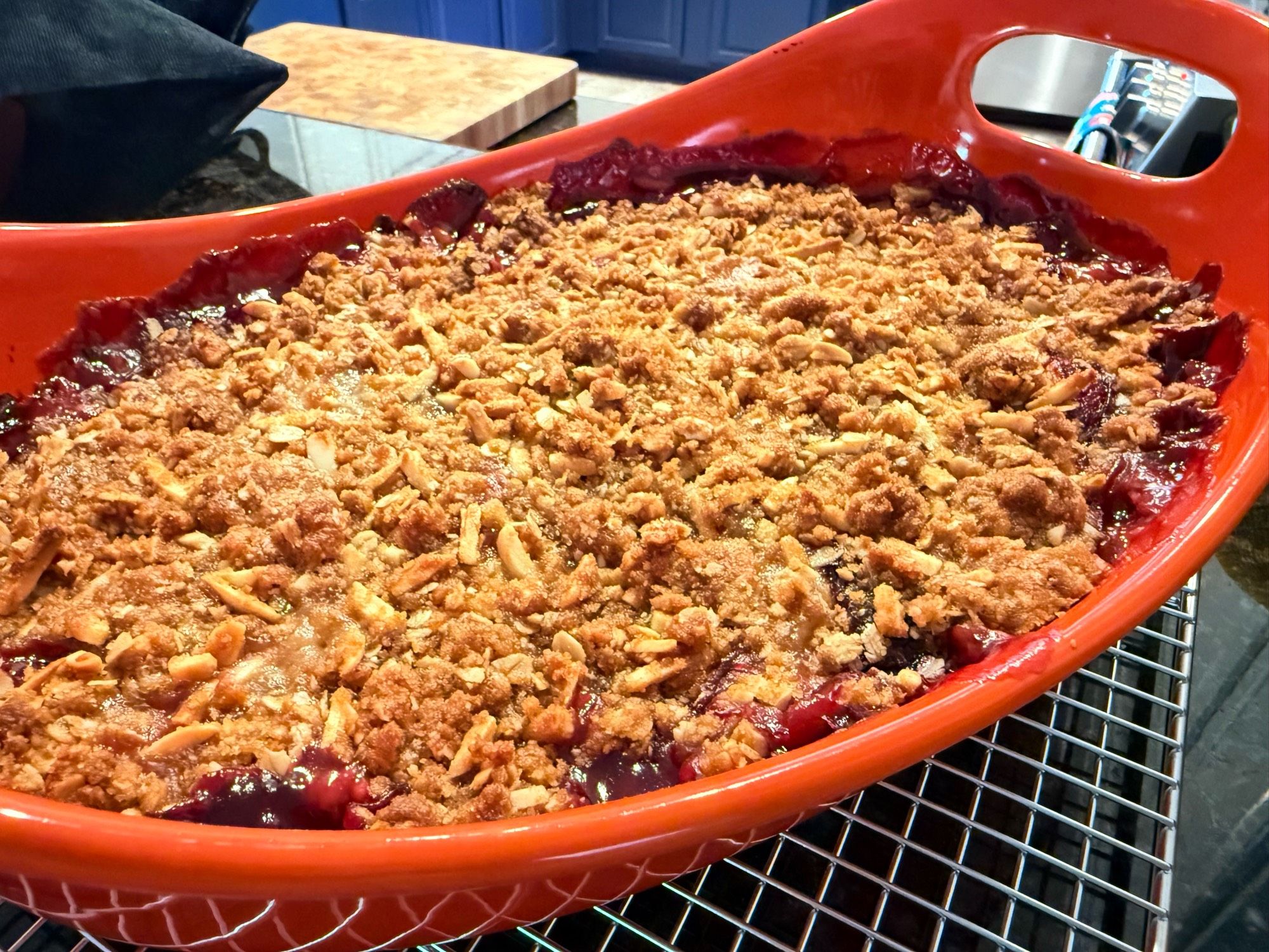 The baked golden brown crumble, with peeks of dark red fruit filling bubbled up through the topping around the edges 