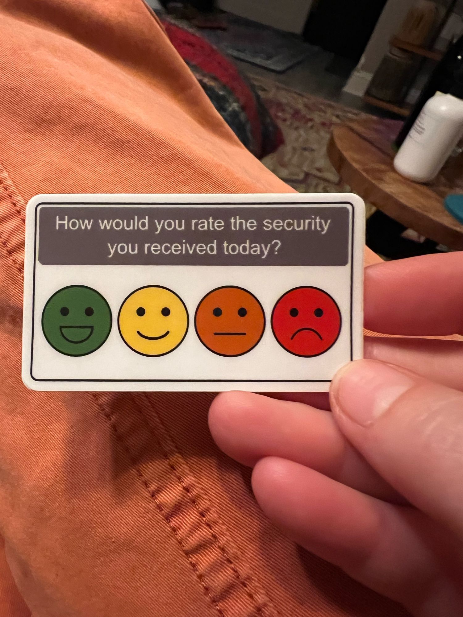 A small sticker which says, “How would you rate the security you received today?” followed by a scale of faces ranging from a green happy face to a red sad face