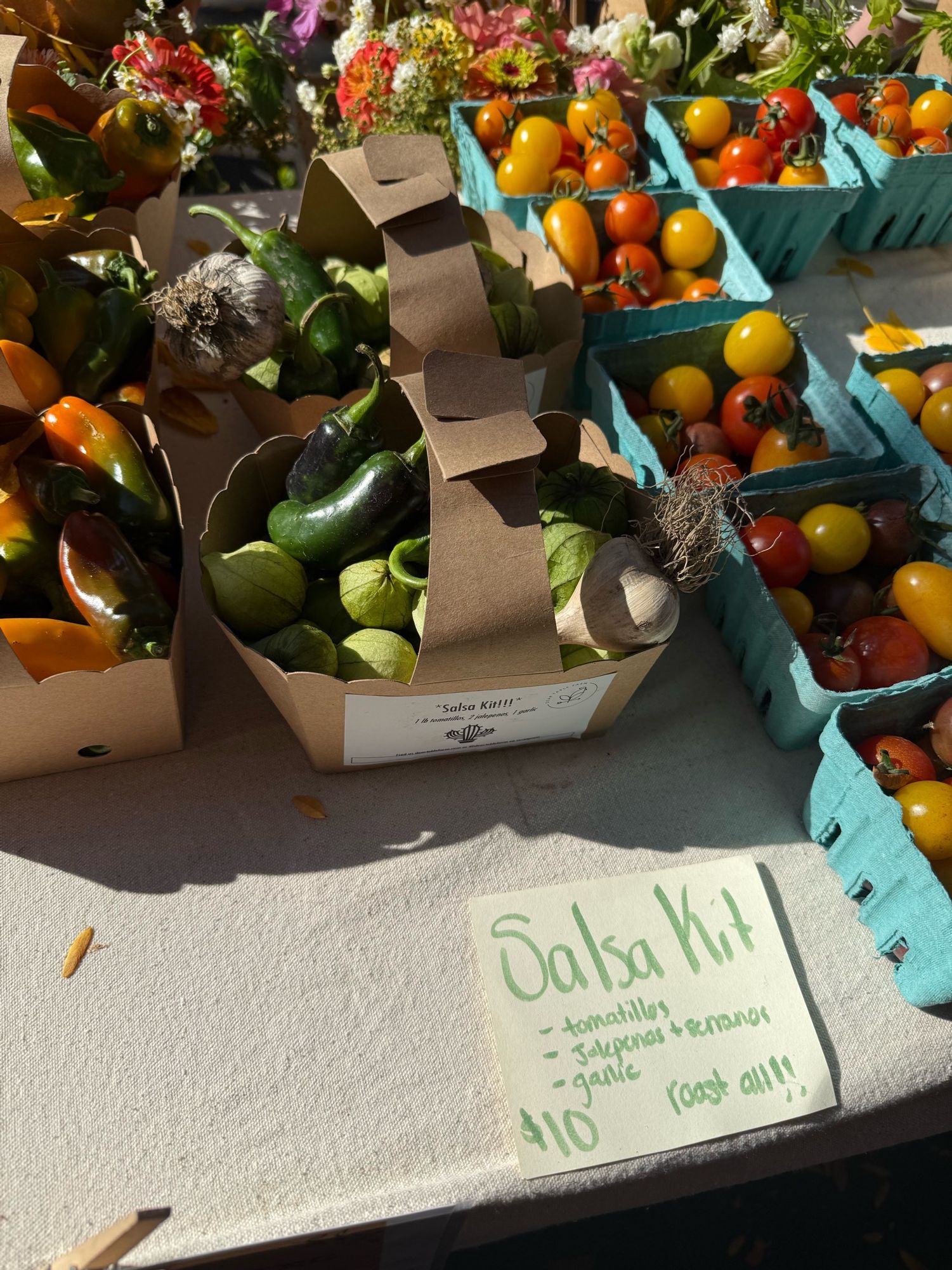 A lil basket labeled “Salsa kit” with tomatillos, jalapeños, serranos and garlic