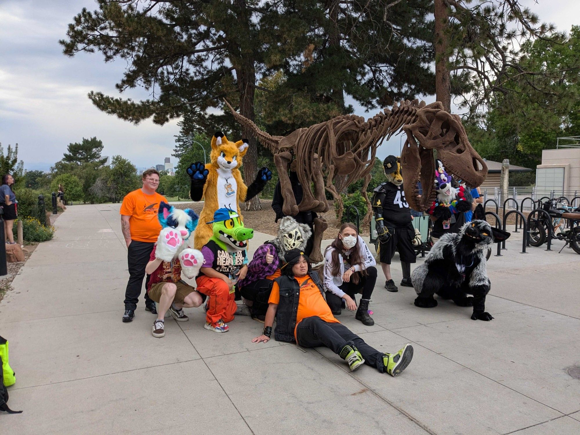 Group shot in front of a t-rex statue. 5-6 fursuits with several non-suiting furries.