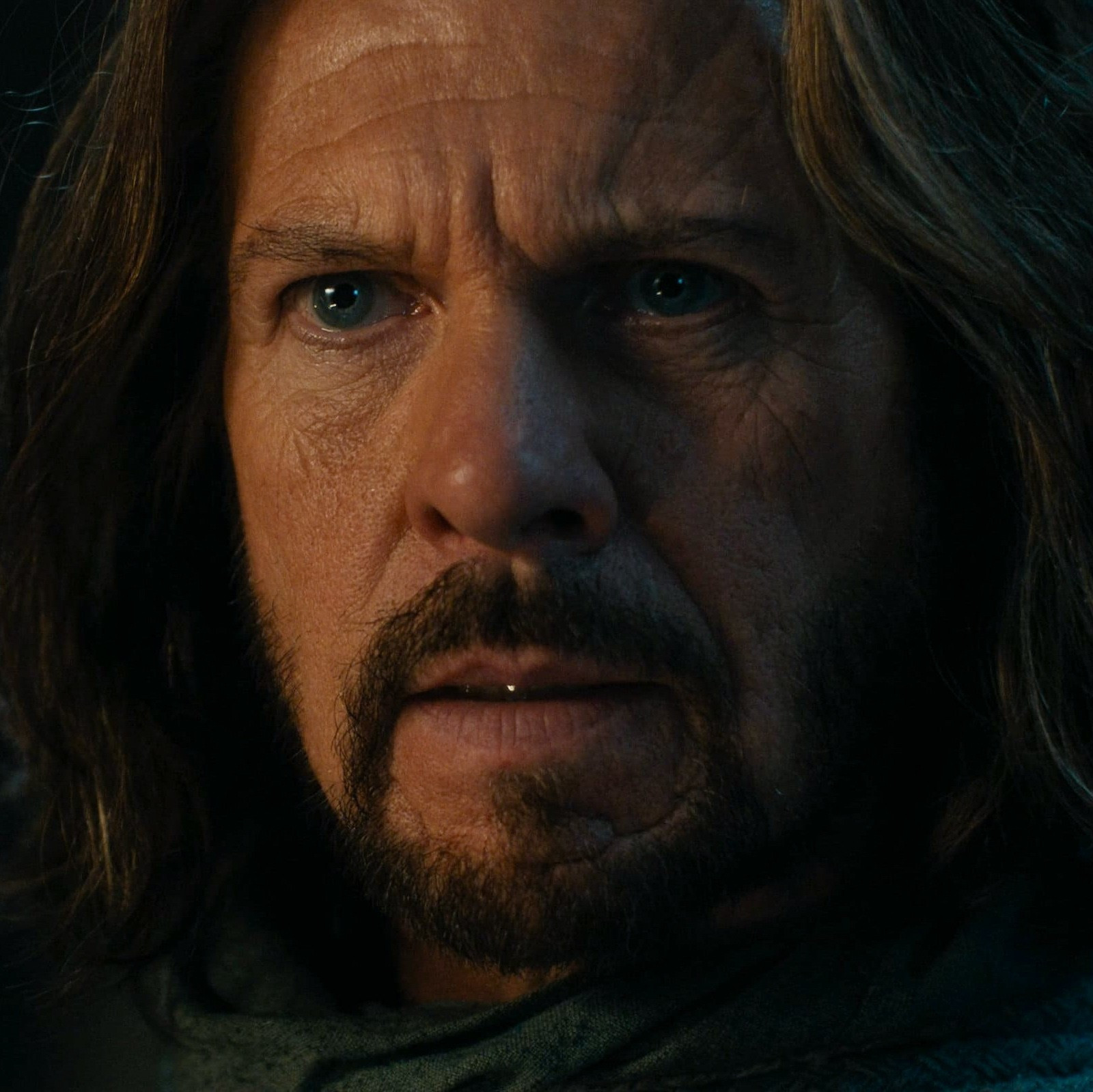 a close up screenshot of lloyd owen as elendil from season 2 episode 8 of the rings of power. he is wearing a look of mild shock and distress.