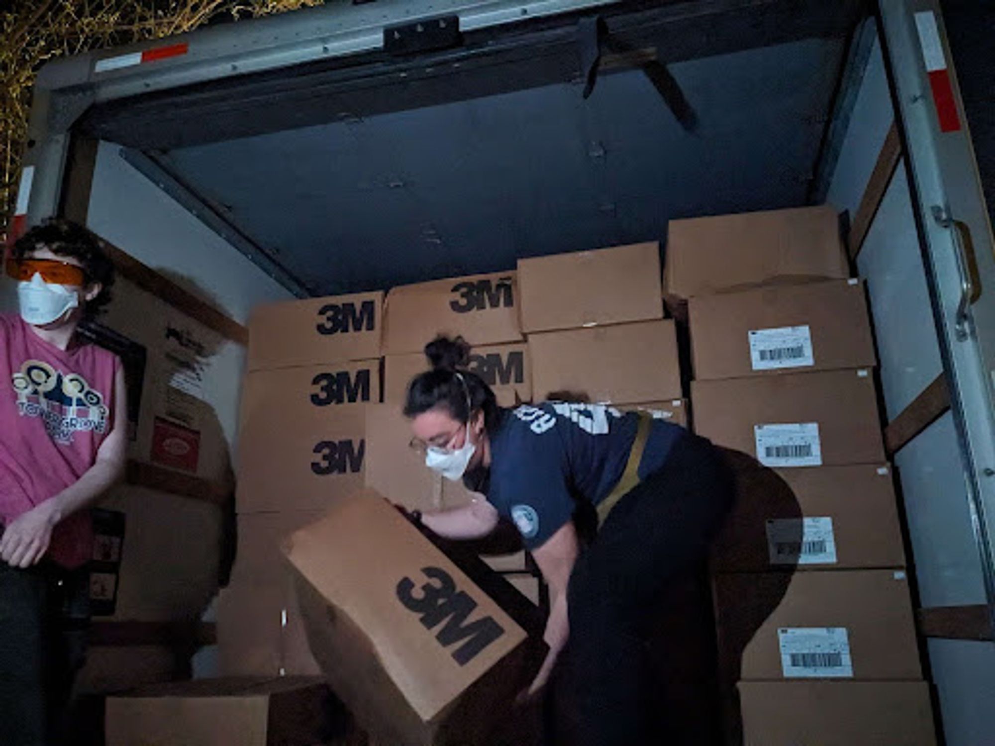 Maskbloc STL members unloading the boxes of masks from the UHaul in St. Louis. They are both wearing n95 masks.