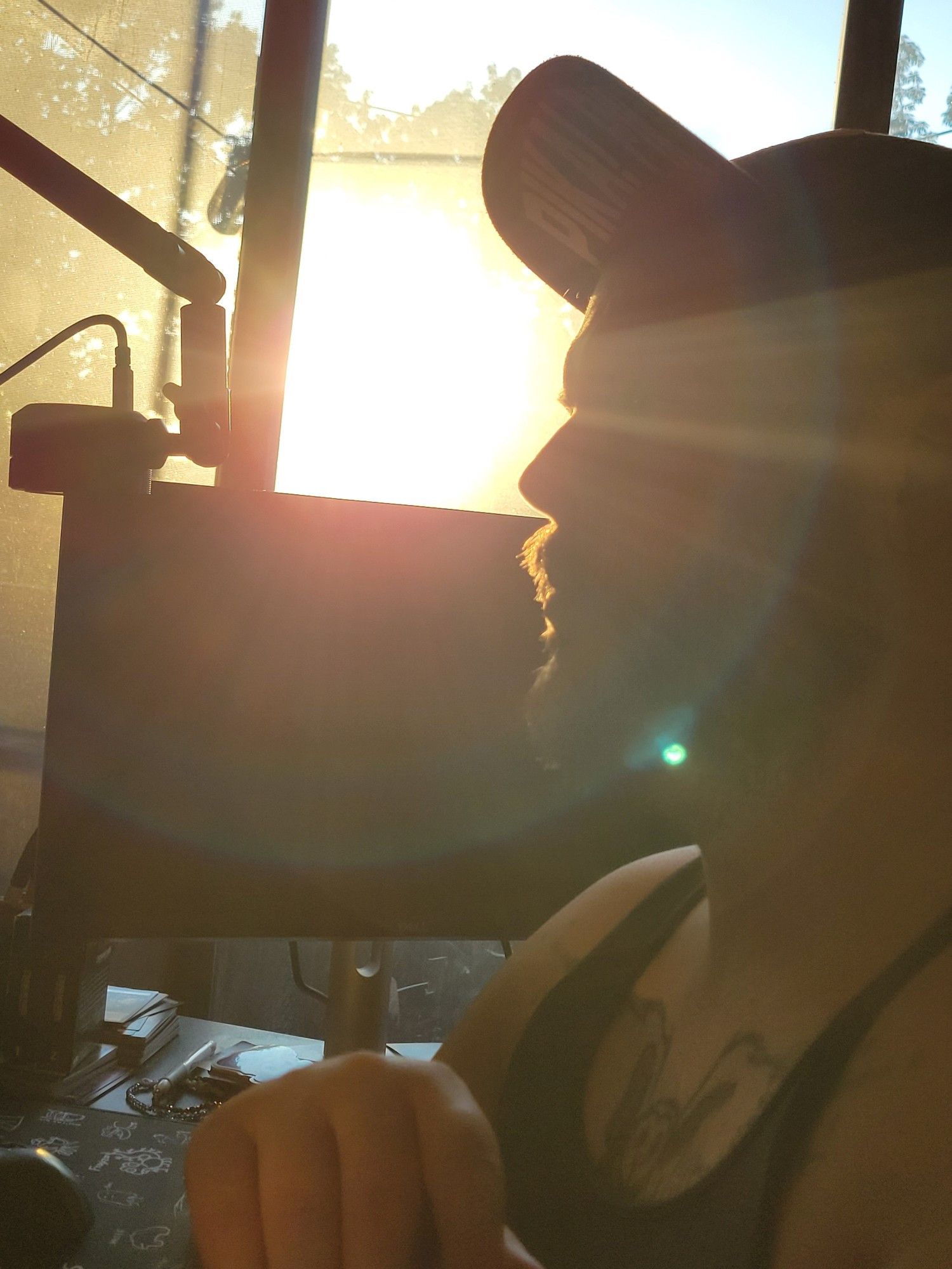 Sunset portrait shot of Benji in a hat and tank top. You can see computer equipment next to him. 