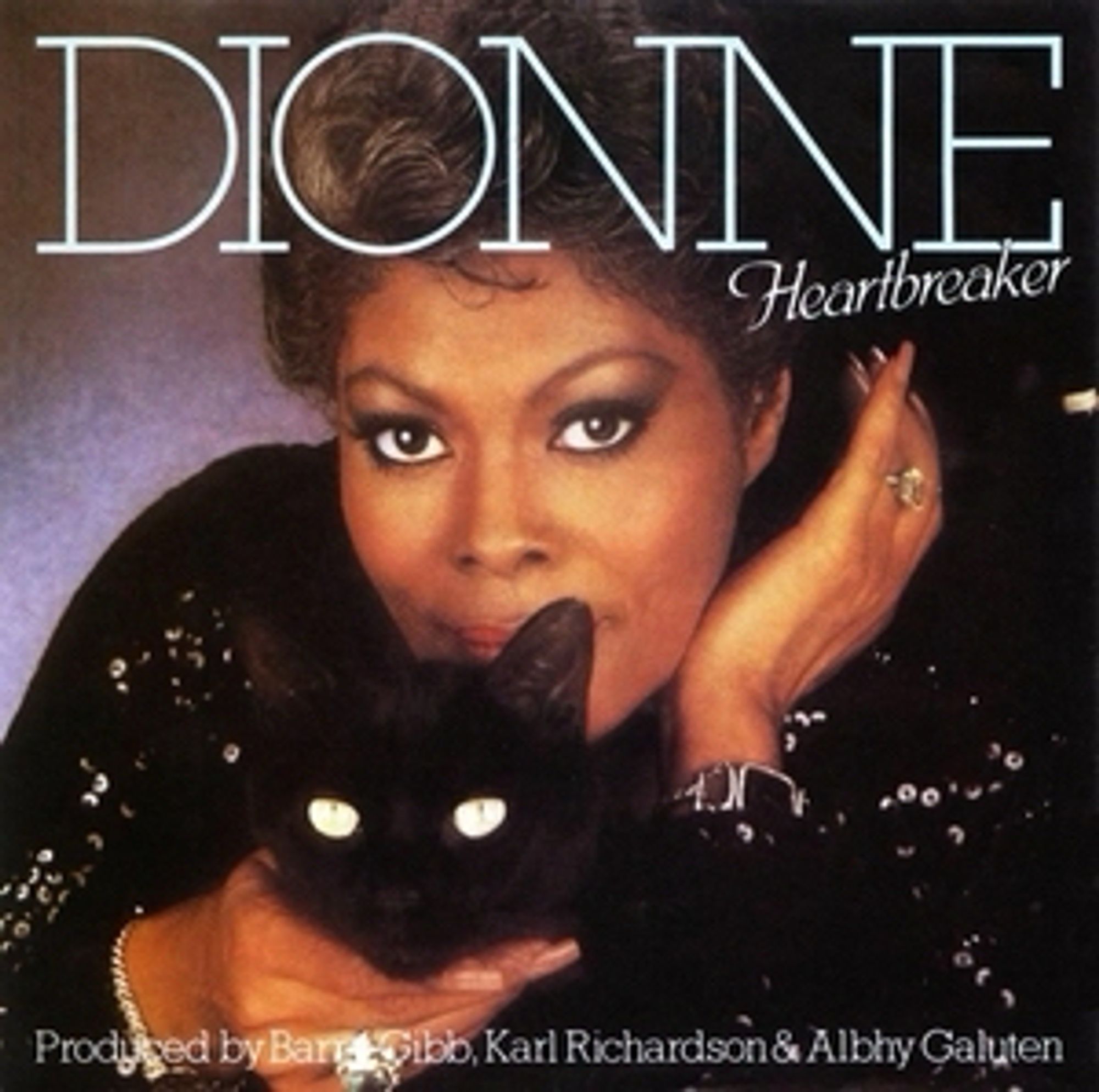 The cover of the Dionne Warwick single Heartbreaker from 1982. A headshot of Dionne wearing a black sequinned dress or top, holding a black cat. Both stare down the lens, both look fabulous. The photo has been shot in a studio. Over Dionne’s shoulder is a mottled background that reeks of school photo day, or a paint effect from a 90s home makeover show. The cat is judging you. It knows you use too many mixed metaphors. Where are its treats, you nincompoop?