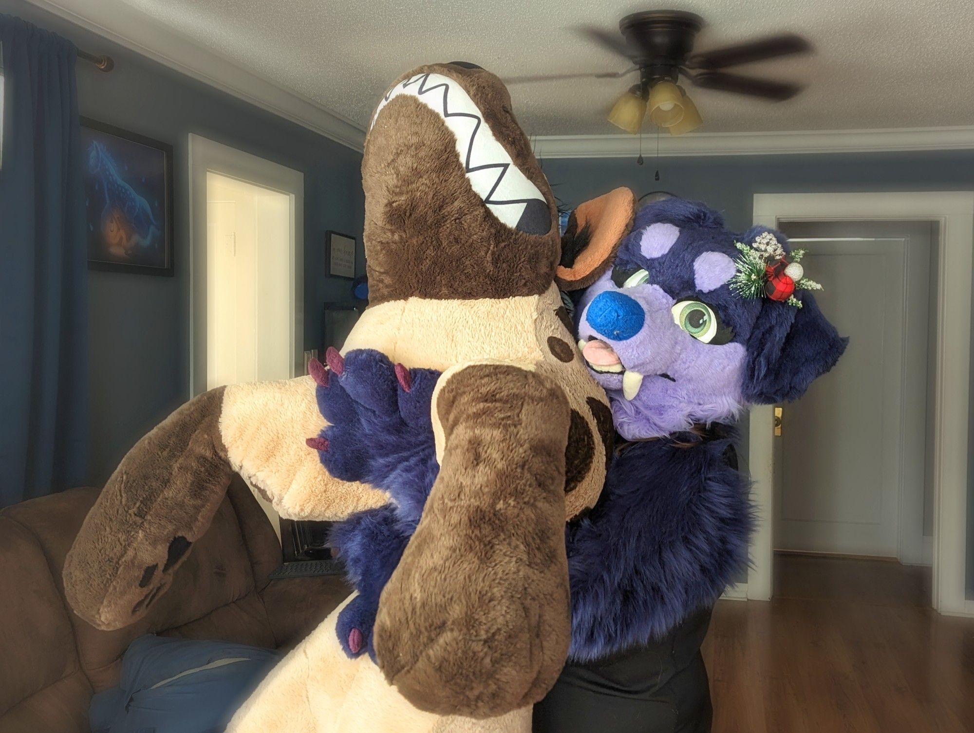 A photo of a person in a purple dog fursuit holding a 6ft hyena plushie