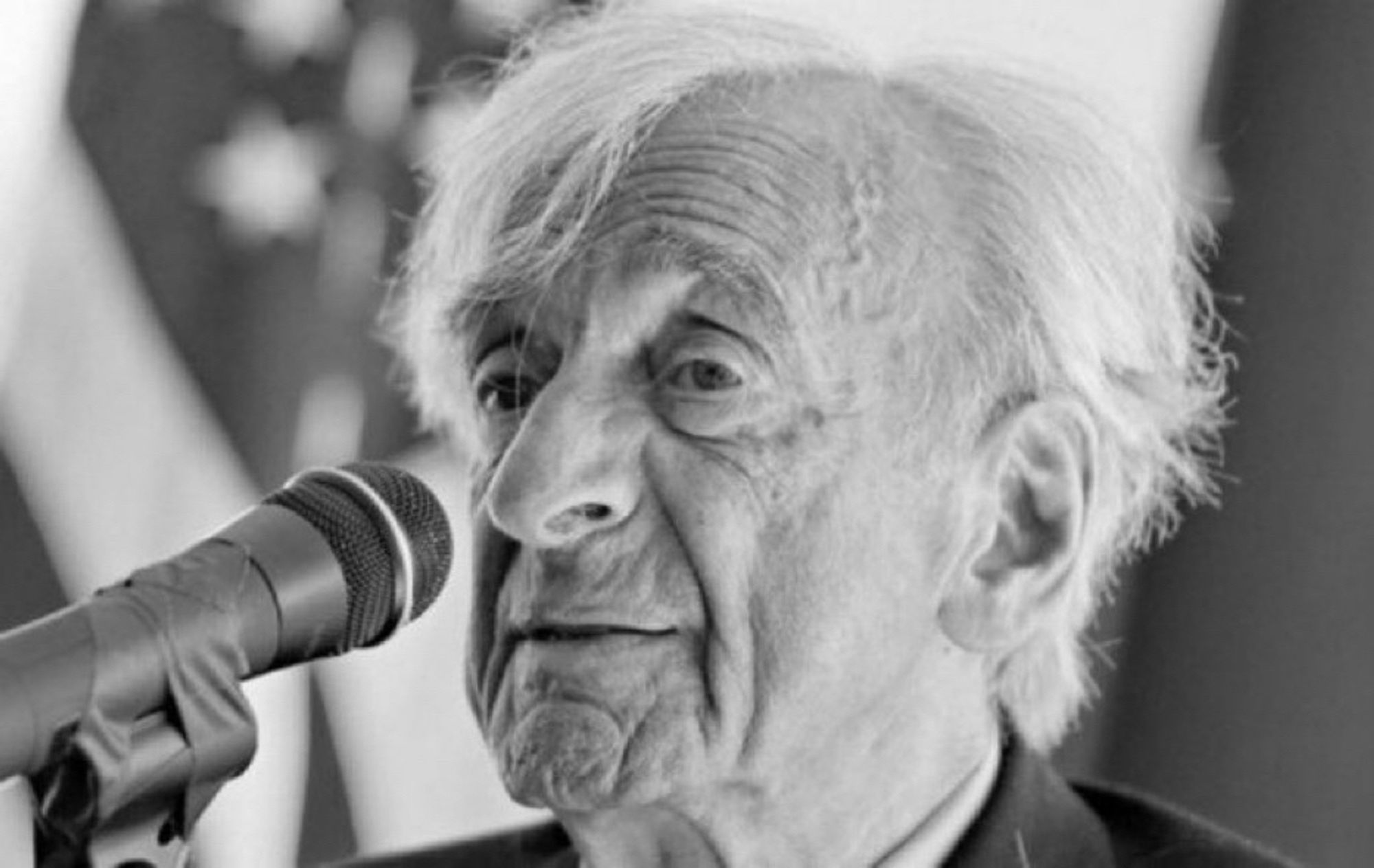 Elie Wiesel vor einem Mikroskop als alter Mann mit weißen Haaren