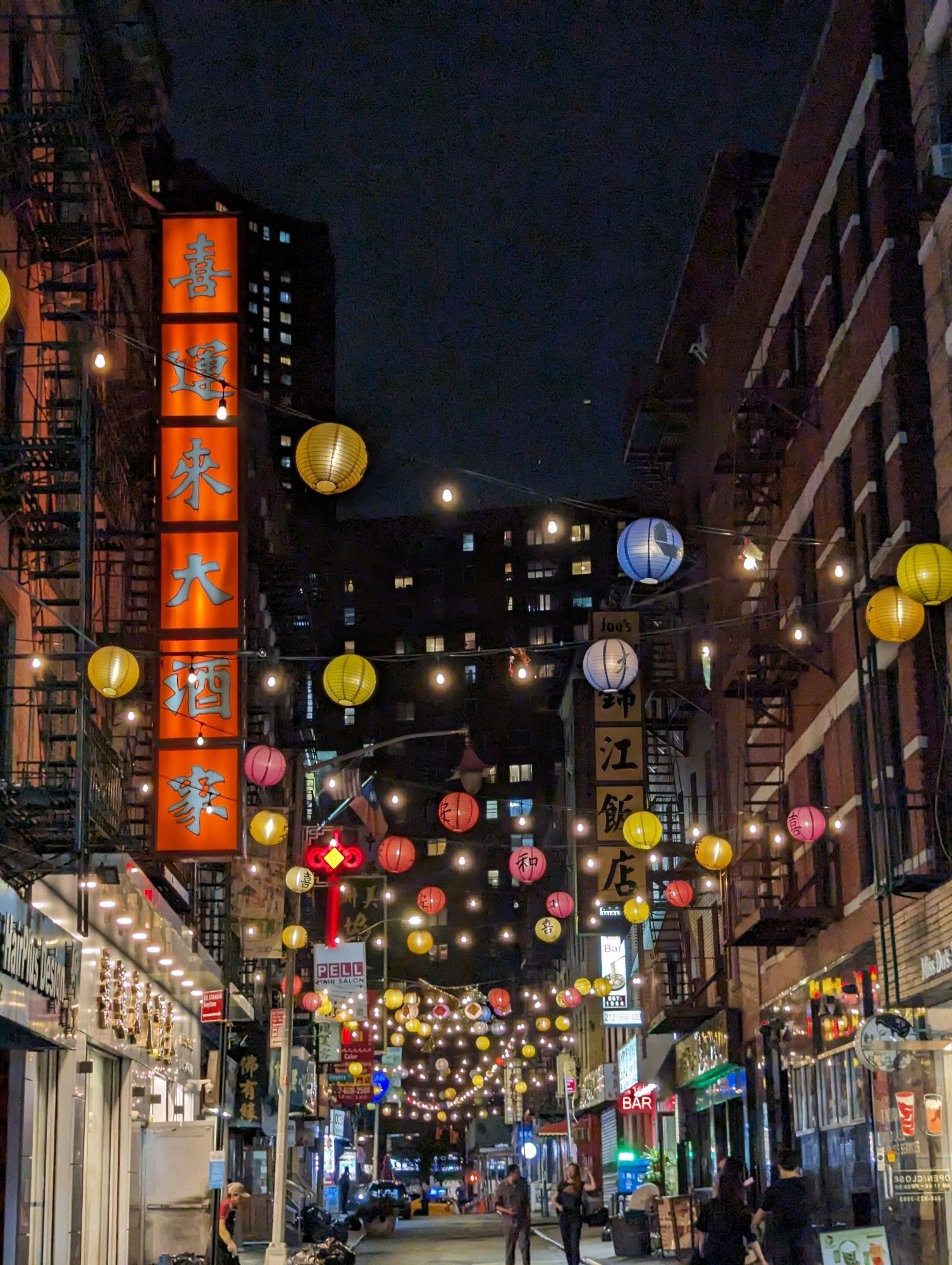 Chinatown in NY at night. Colorful garlands hang across a busy street.