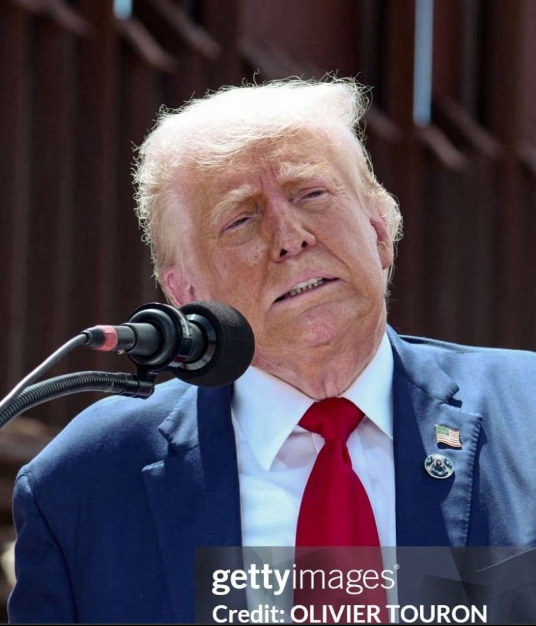 Disgraced former president and convicted felon Donald Trump at a propaganda event in Glendale, AZ, August 23, 2024. He looks haggard and exhausted in a crumpled blue suit and seemingly aware of all the misery he has caused. His once signature orange hair and skin have been stripped to a ghastly white, reminiscent of the Klan robes with which he is no doubt familiar.