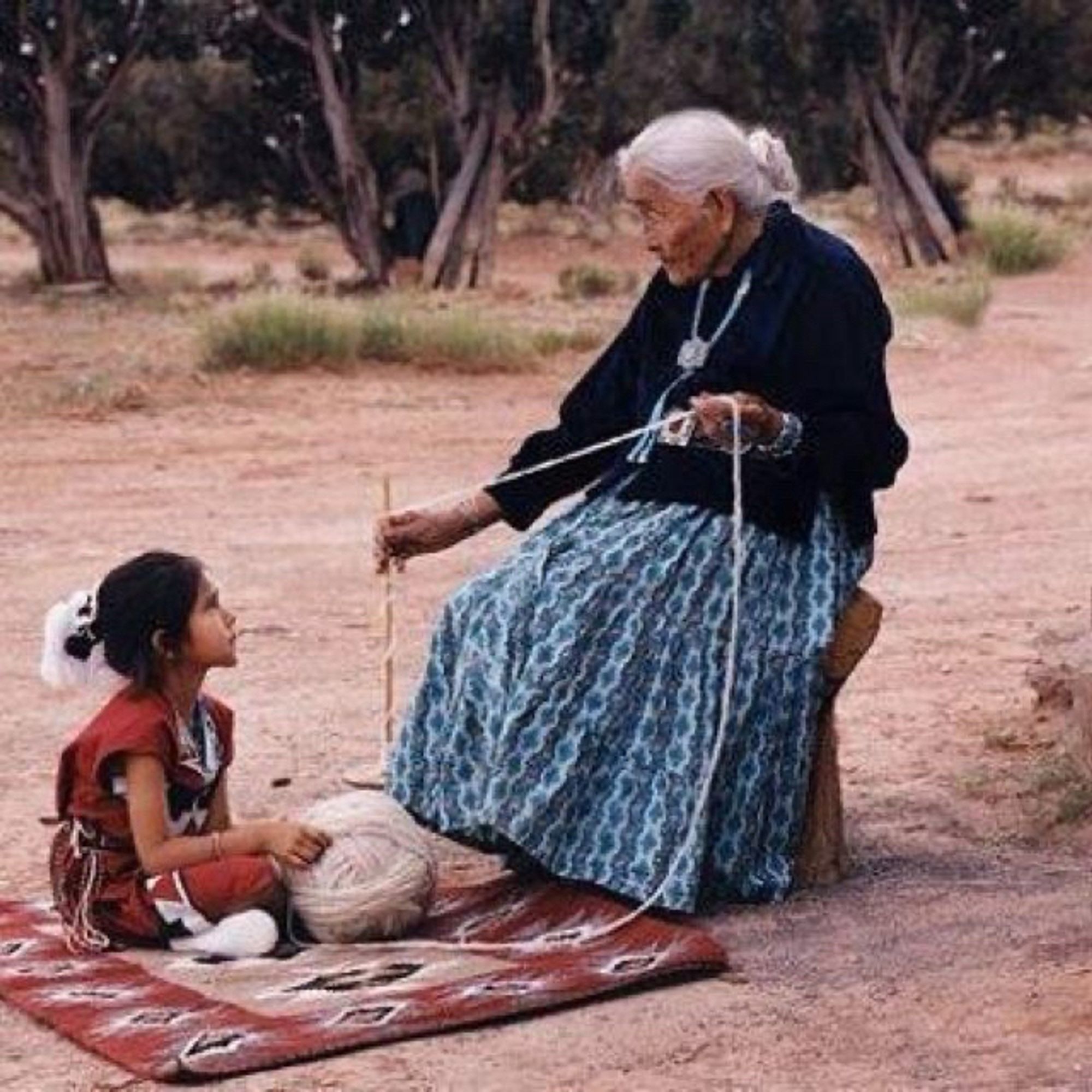 Indigenous grandmother instructs a little girl, possibly her granddaughter.