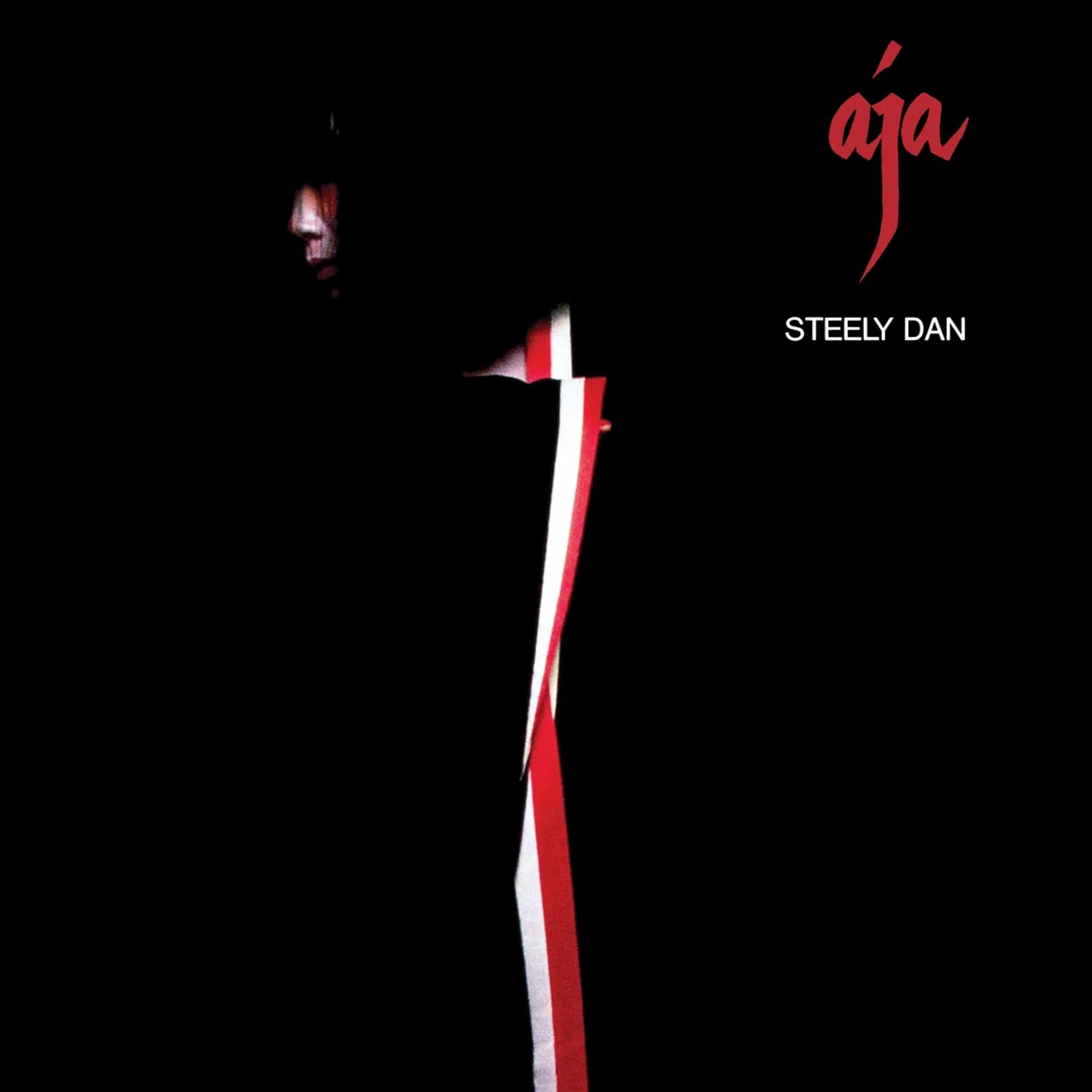 Cover photo of the 1977 Steely Dan album "Aja" featuring an Asian female's face in profile. She appears to be wearing a red and white sash or scarf which bisects the otherwise completely black background.