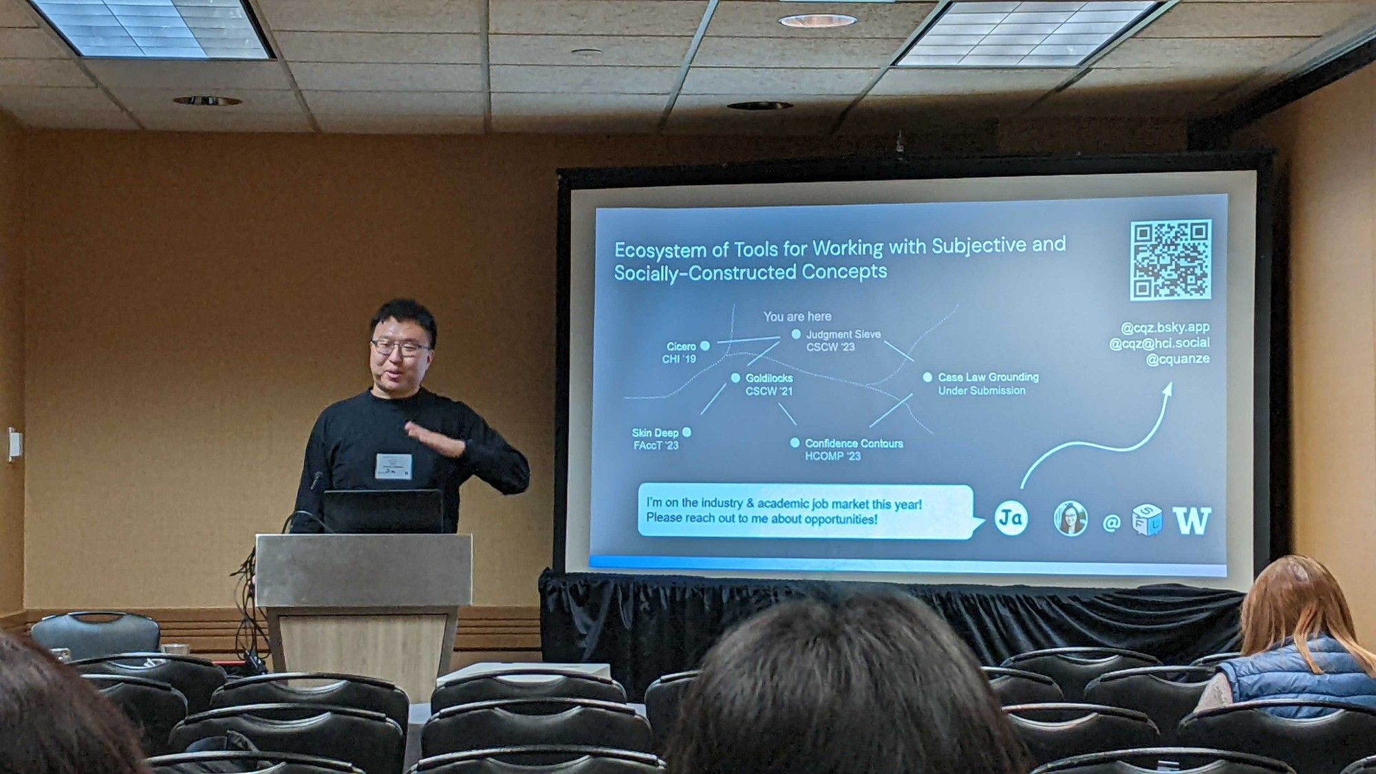 Jim at the podium next to a slide about his research with an audience in front