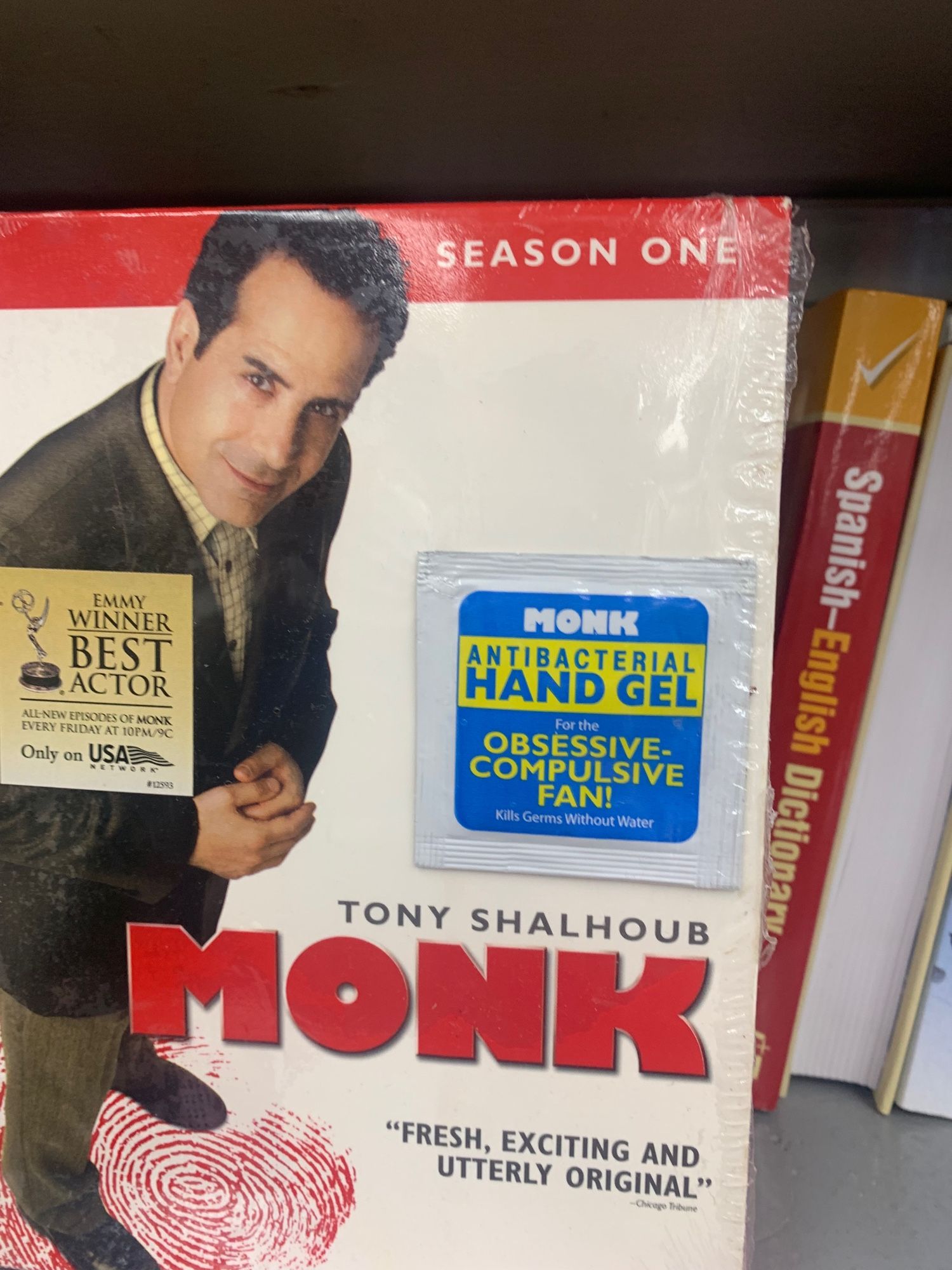 a copy of monk season 1 on dvd at a thrift store, with a packet of hand sanitizer attached to it