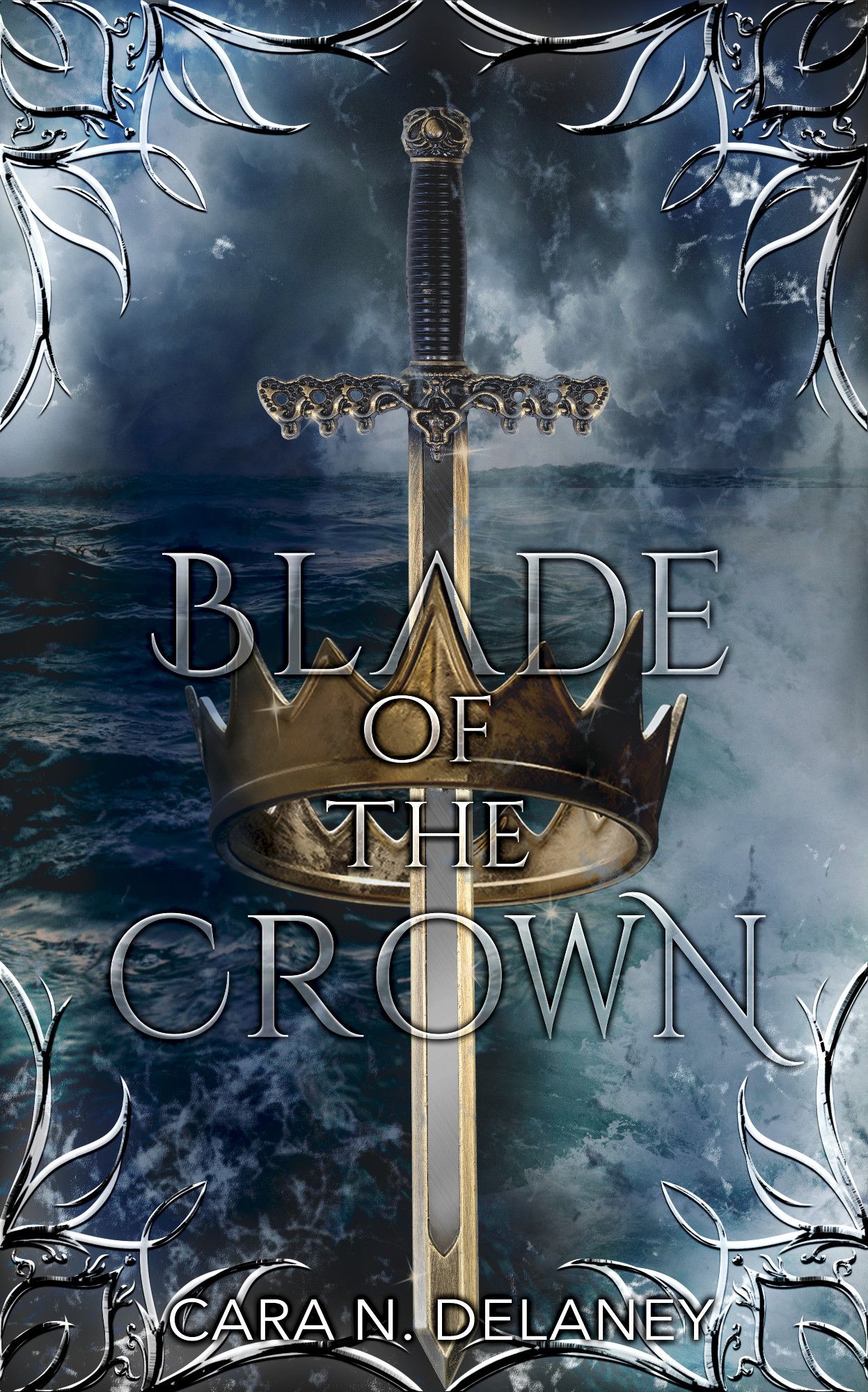 The cover of the book "Blade of the Crown" by author Cara N. Delaney. The background is the ocean, choppy with waves. The sky is grey and dark blue with storm clouds. Silver ornaments decorate the corners and the top and bottom edges. In the foreground is a golden crown in a classic shape. A slender sword with an ornamental cross guard goes through it vertically. The title is written in a silver, slightly translucent font, with one point of the crown filling the "A" of "blade". The author's name is in white at the bottom.