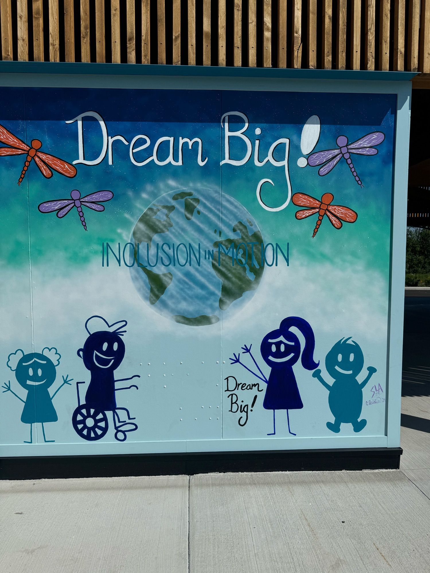 Mural earth and children playing titled “dream big! Inclusion in motion”