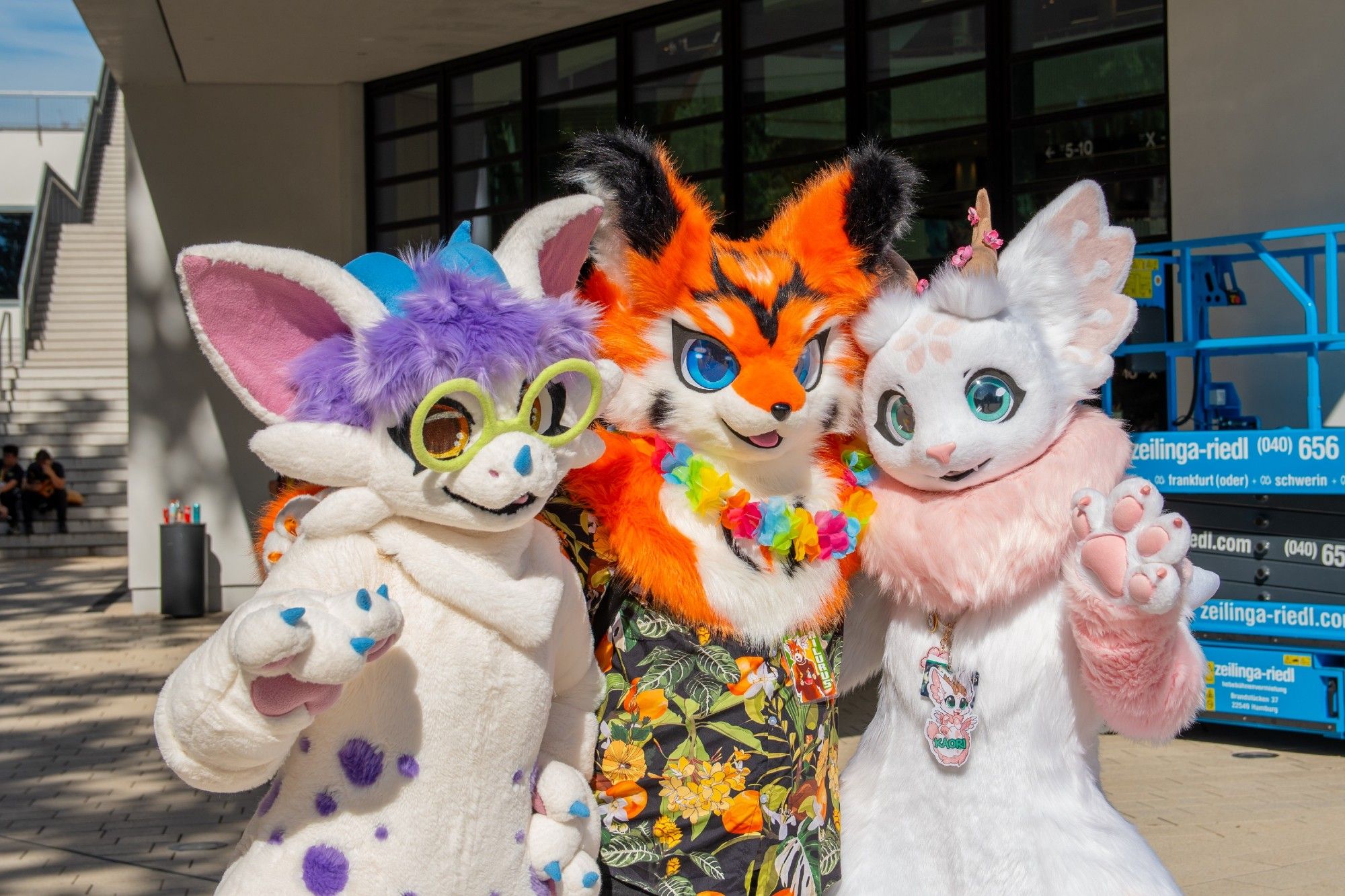 An orange fox with blue eyes and a Hawaiian shirt stands in the middle of two cute furred dragons, a white axolotl dragon with purple hair and blue horns on the left and a white spring dragon with pink markings and horns decorated with cherry blossoms on the right.