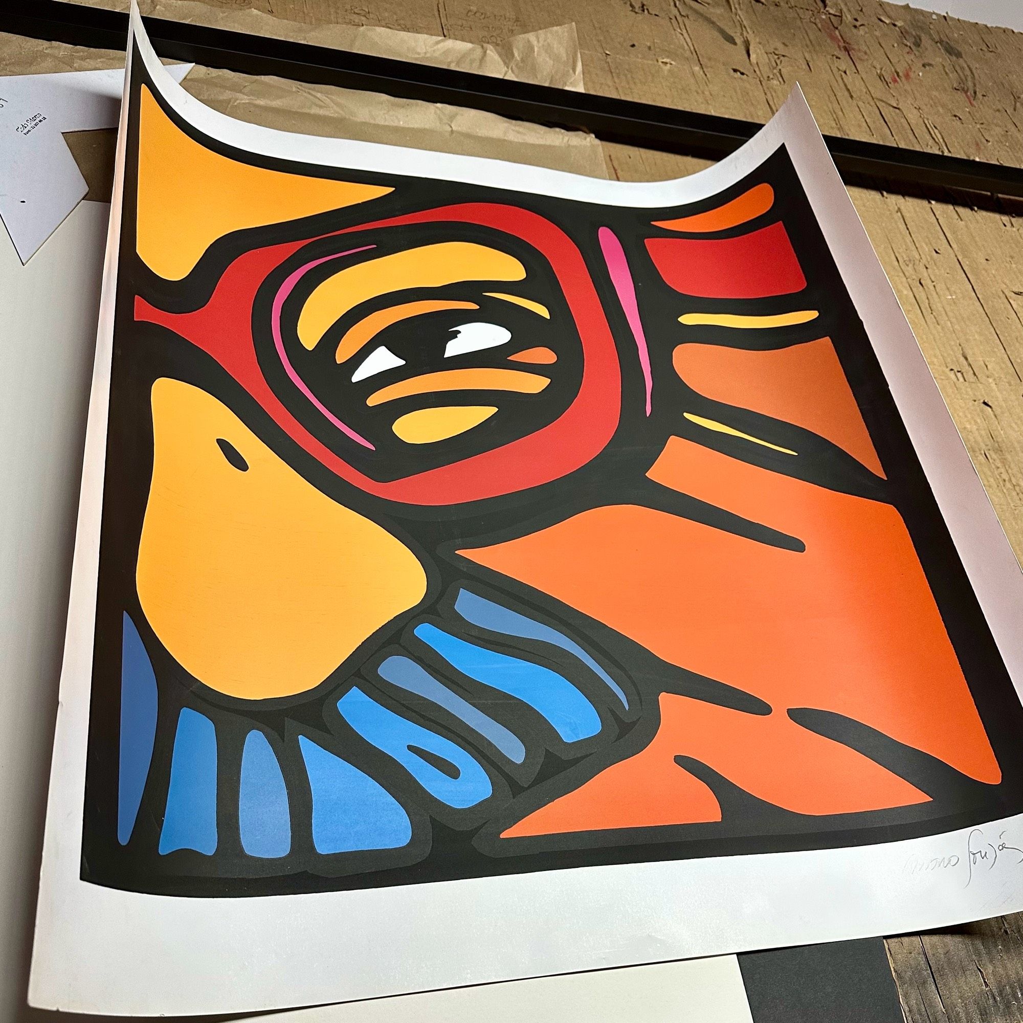 A serigraph of Salvador Allende in various colors on a table in a framing workshop with matting board and framing materials.