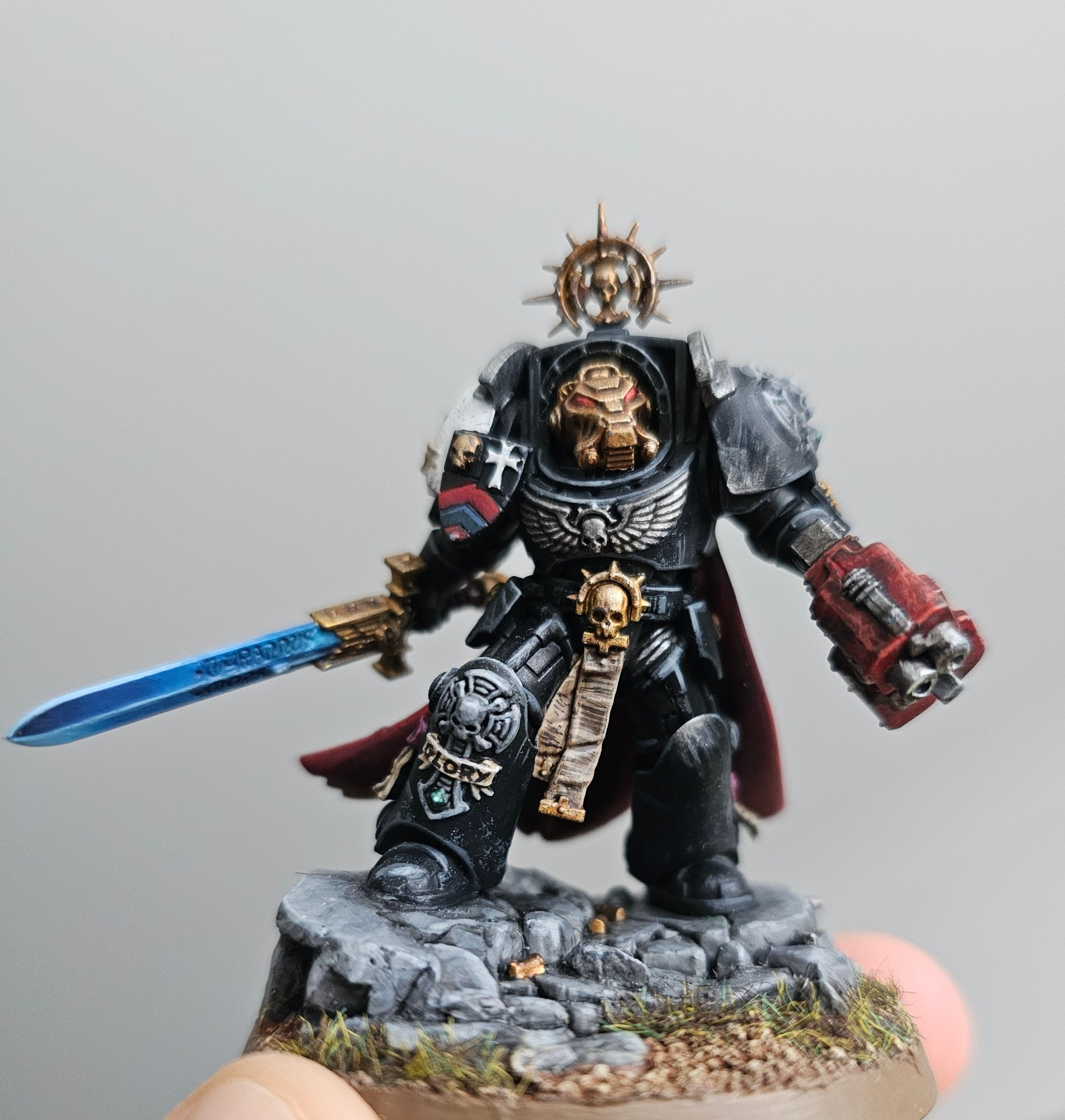 Warhammer model in black armour with a gun and sword.