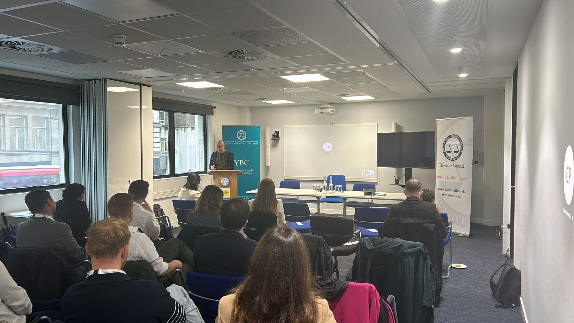 an audience of around 20 people listening to a speaker