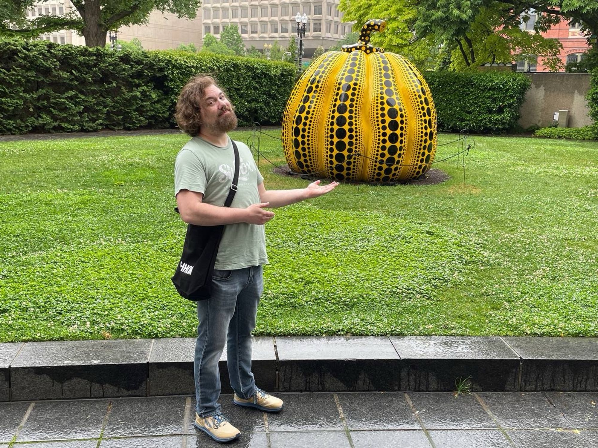 Sebastian standing next to a large yellow and black pumpkin sculpture by Kusama