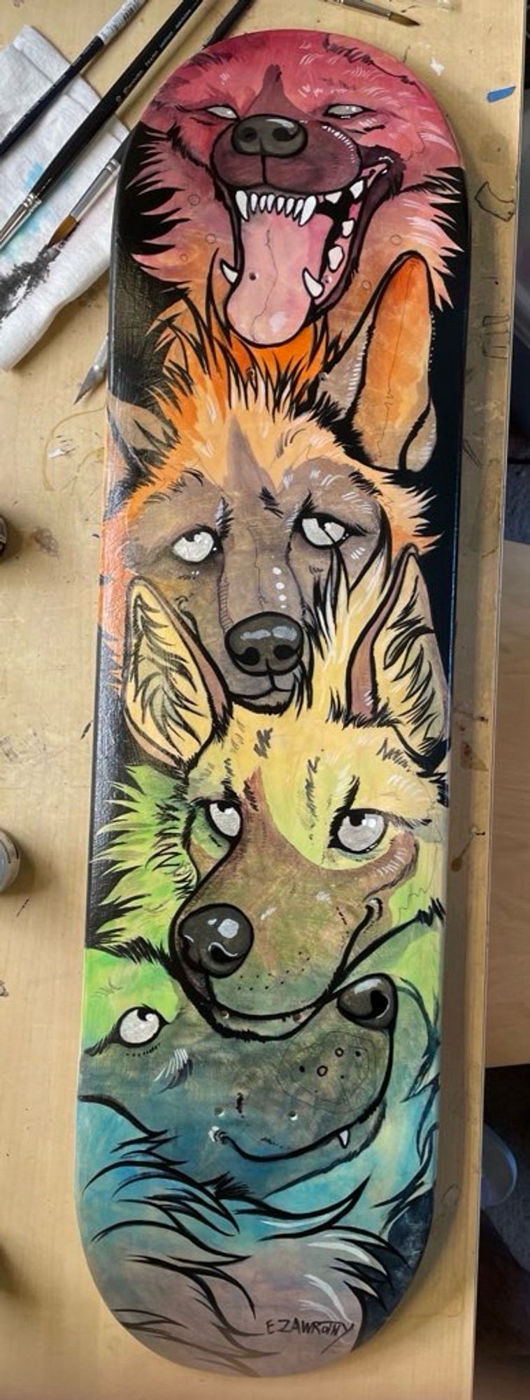 rainbow hyena faces painted on a skate deck