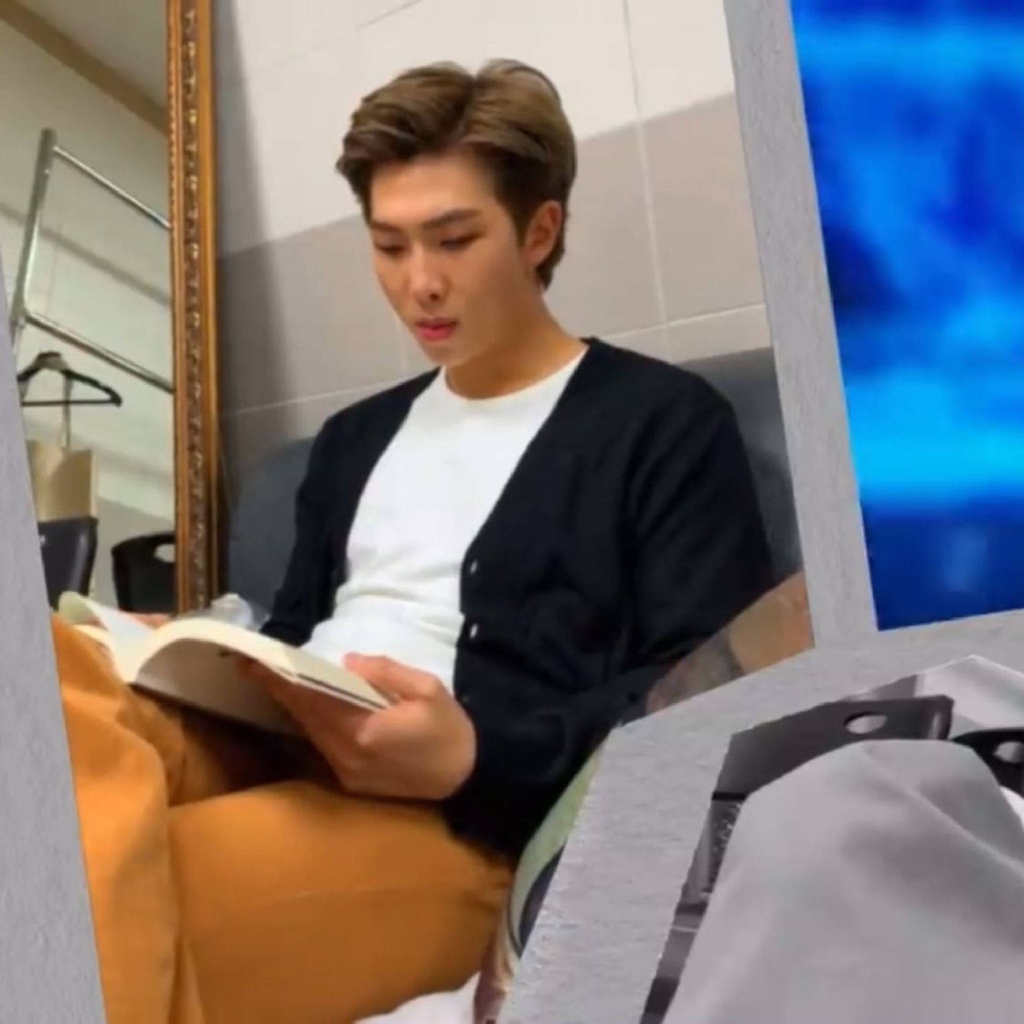 RM in orange trousers white T-shirt and black sweater reading...