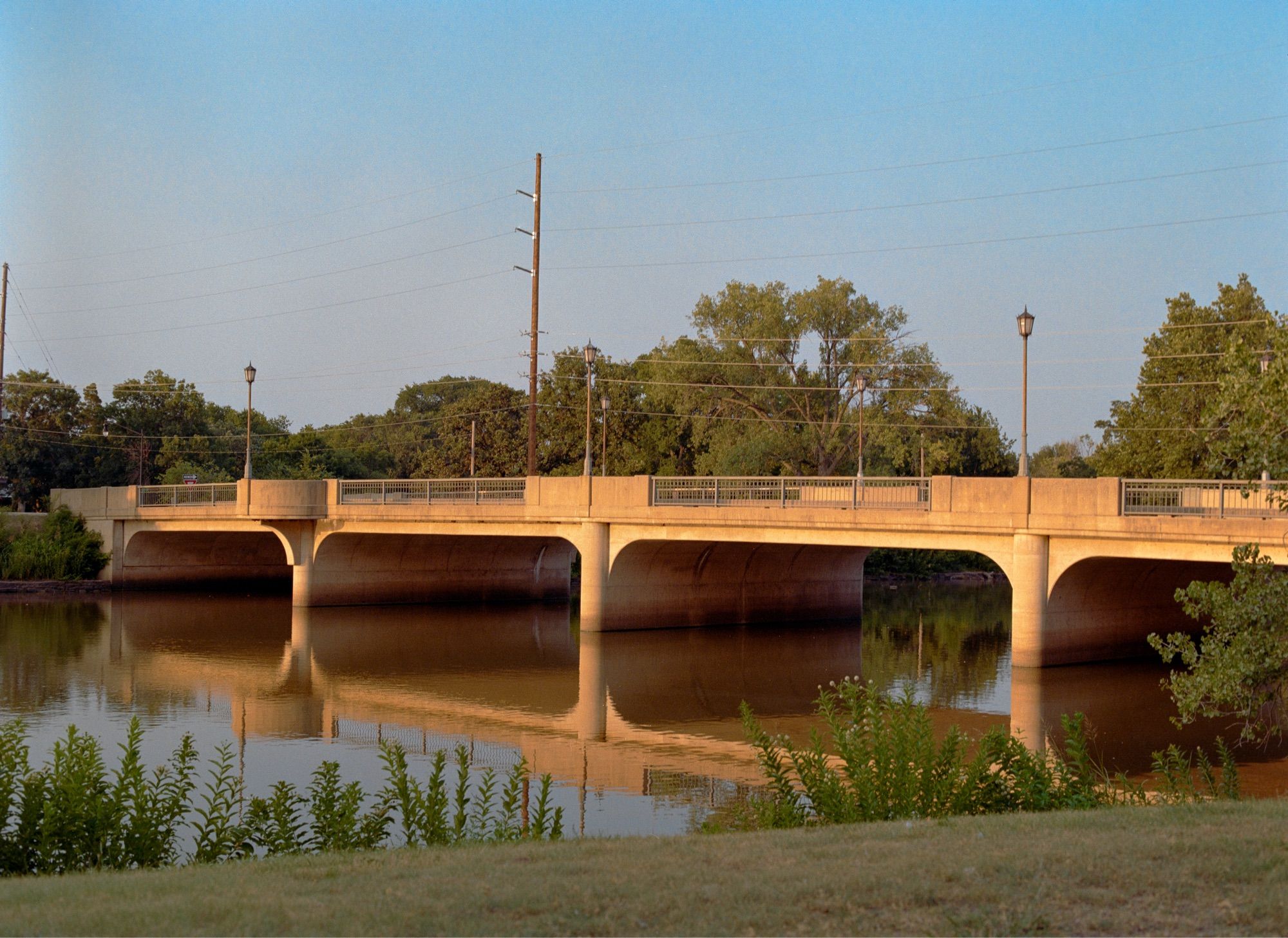 A film photograph of a bridge over a river in a city.