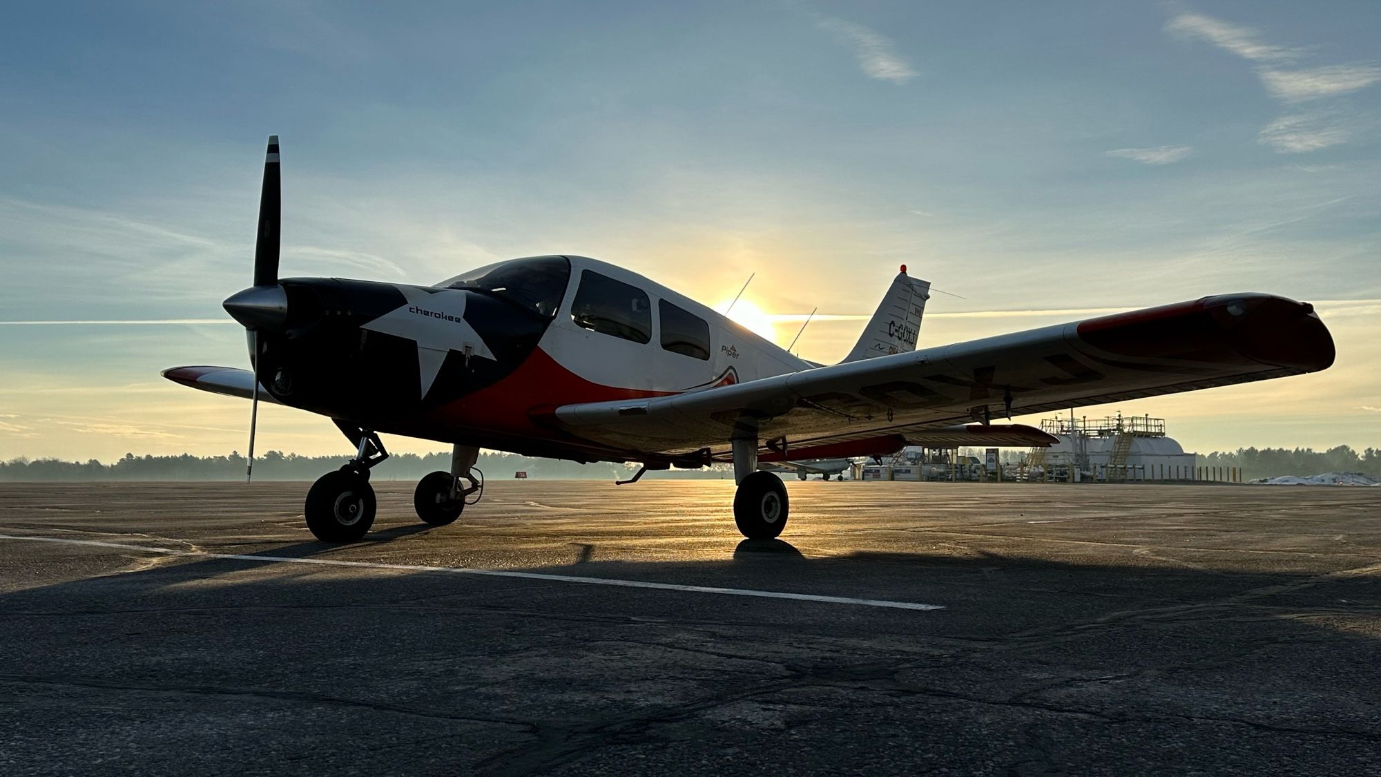 Piper Cherokee PA-28-140 sitting on the ramp at CYQA with sun and mist in the background.