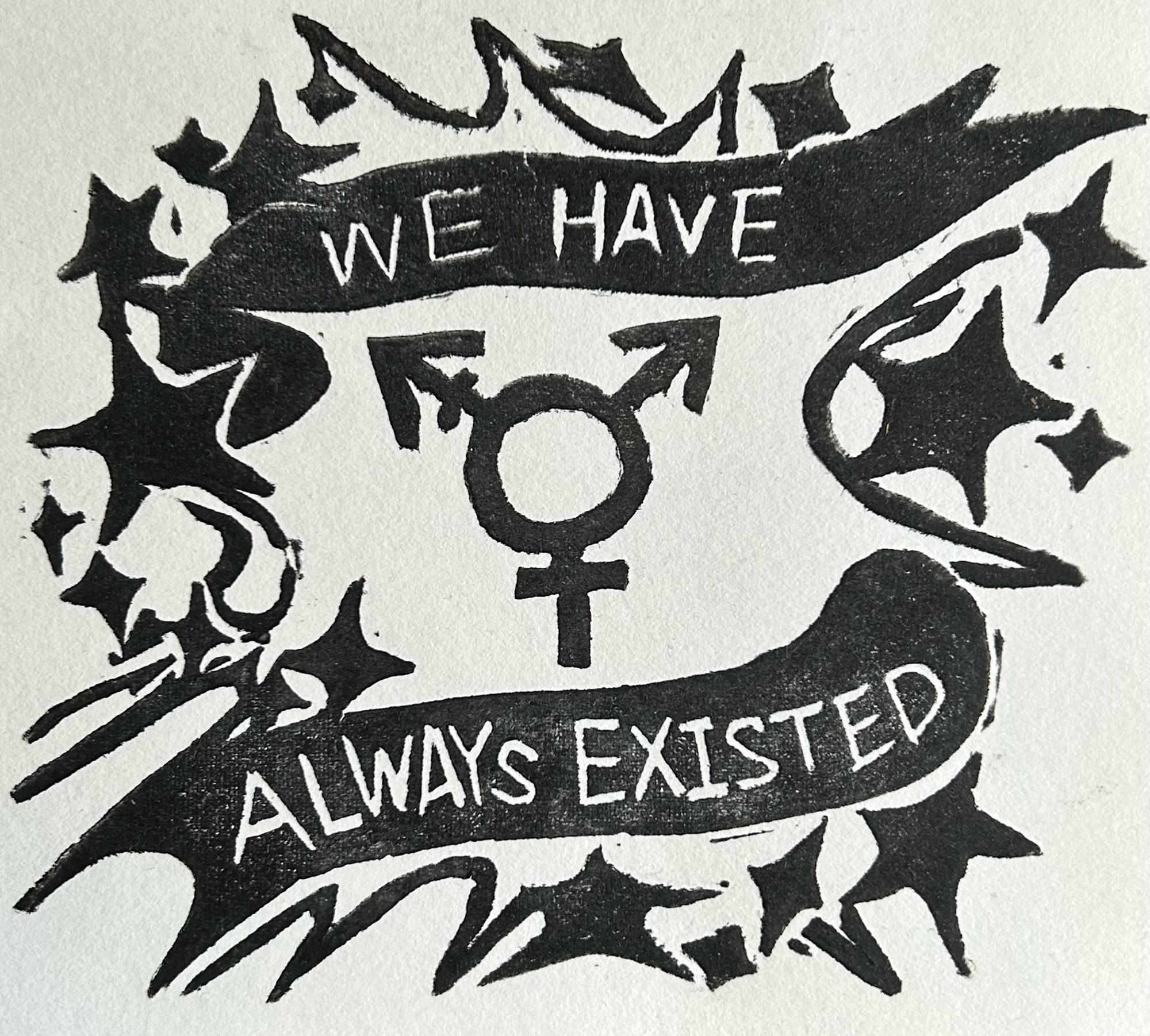 Black ink stamped on white paper. The image is a transgender symbol with the words “WE HAVE ALWAYS EXISTED” wrapping around it. Star and starburst shapes surround it.