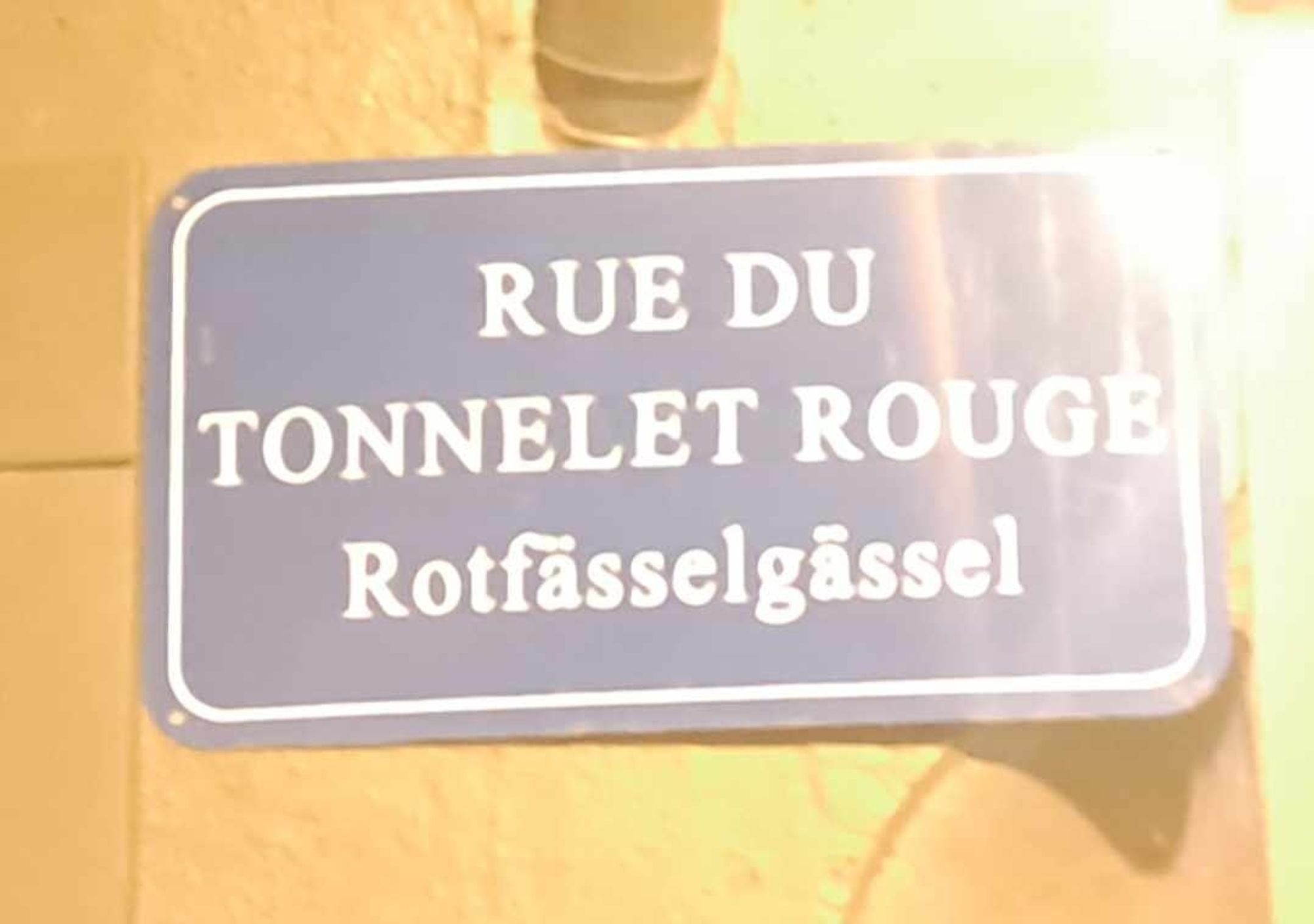 Skylt med texten RUE DU TONNELET ROUGE på franska och Rotfässelgässel på elsassiska [lilla röda tunnans lilla gränd]