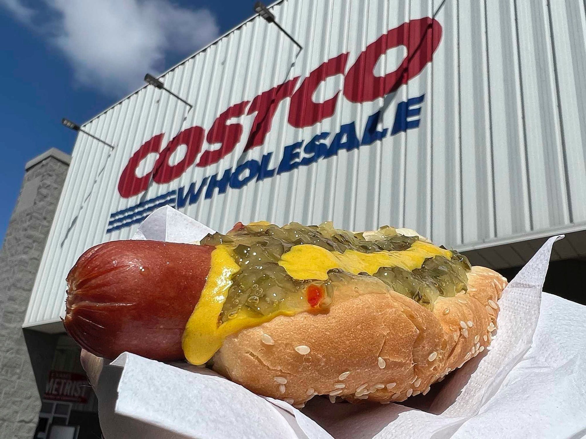 a hot dog on a bun with mustard and relish

in the background is costco wholesale