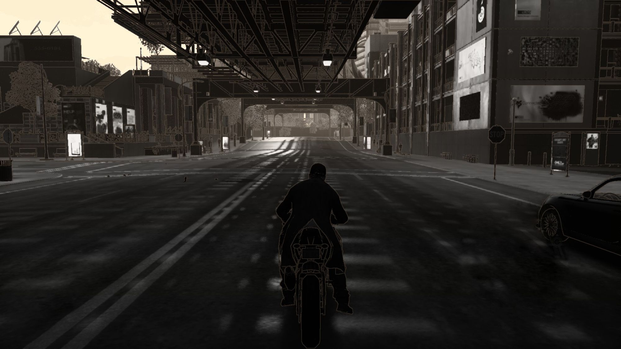 A motorcyclist rides through a dark city street under an overpass, with buildings and a parked car nearby.