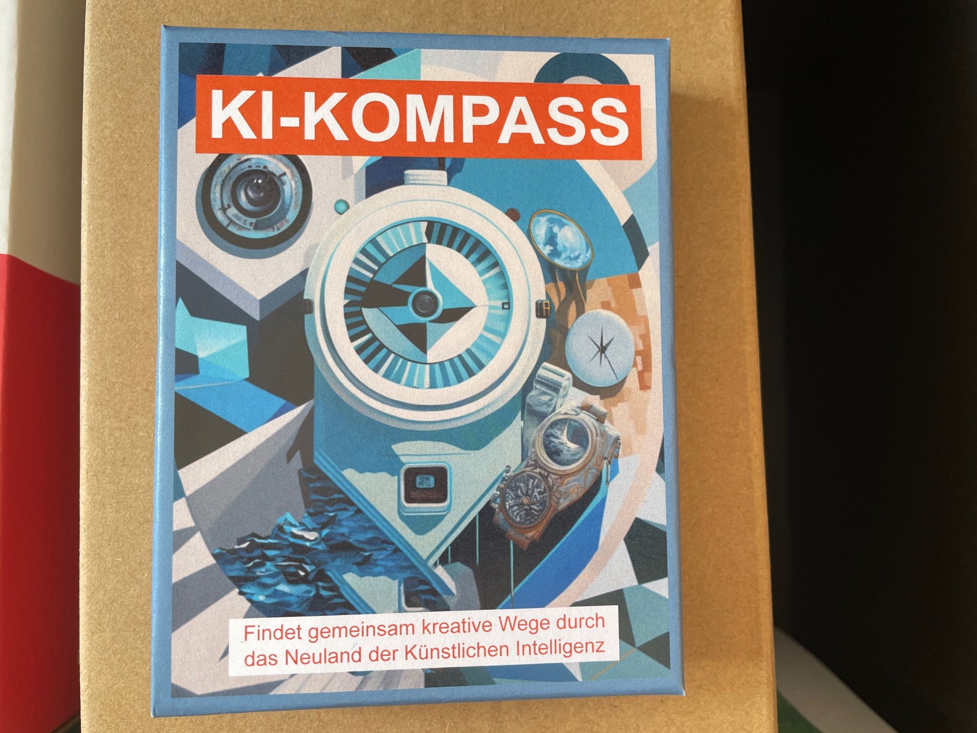 Zu sehen ist eine Packung mit der Aufschrift „KI Kompass Findet gemeinsam neue Wege durch das Neuland der künstlichen Intelligenz“.