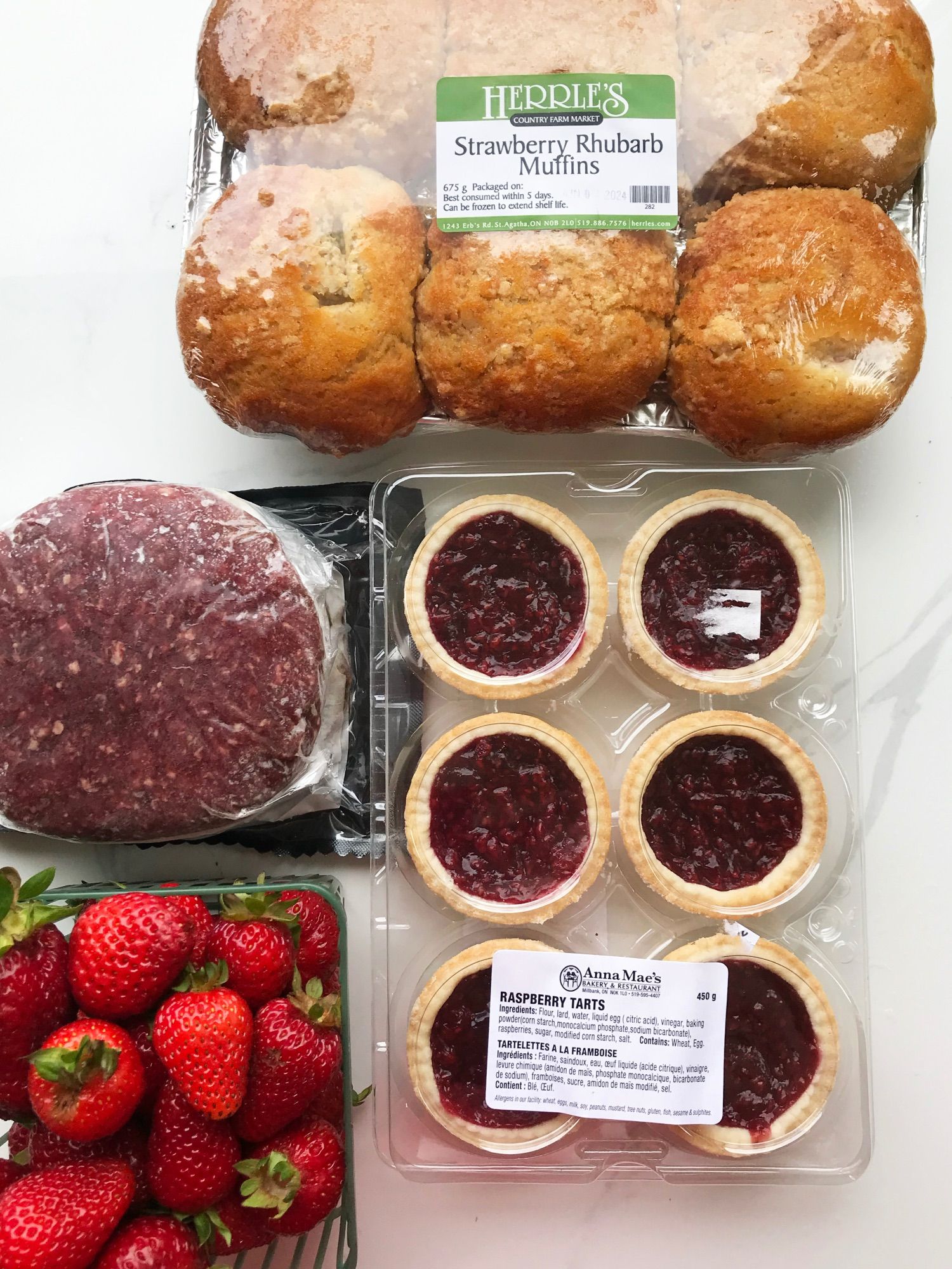 A six-pack of Strawberry Rhubarb muffins and a six-pack of AnnaMae's raspberry tarts (both bought at Herrle's) . A pack of frozen bison burgers and a punnet of strawberries (both from Oakridge Acres).