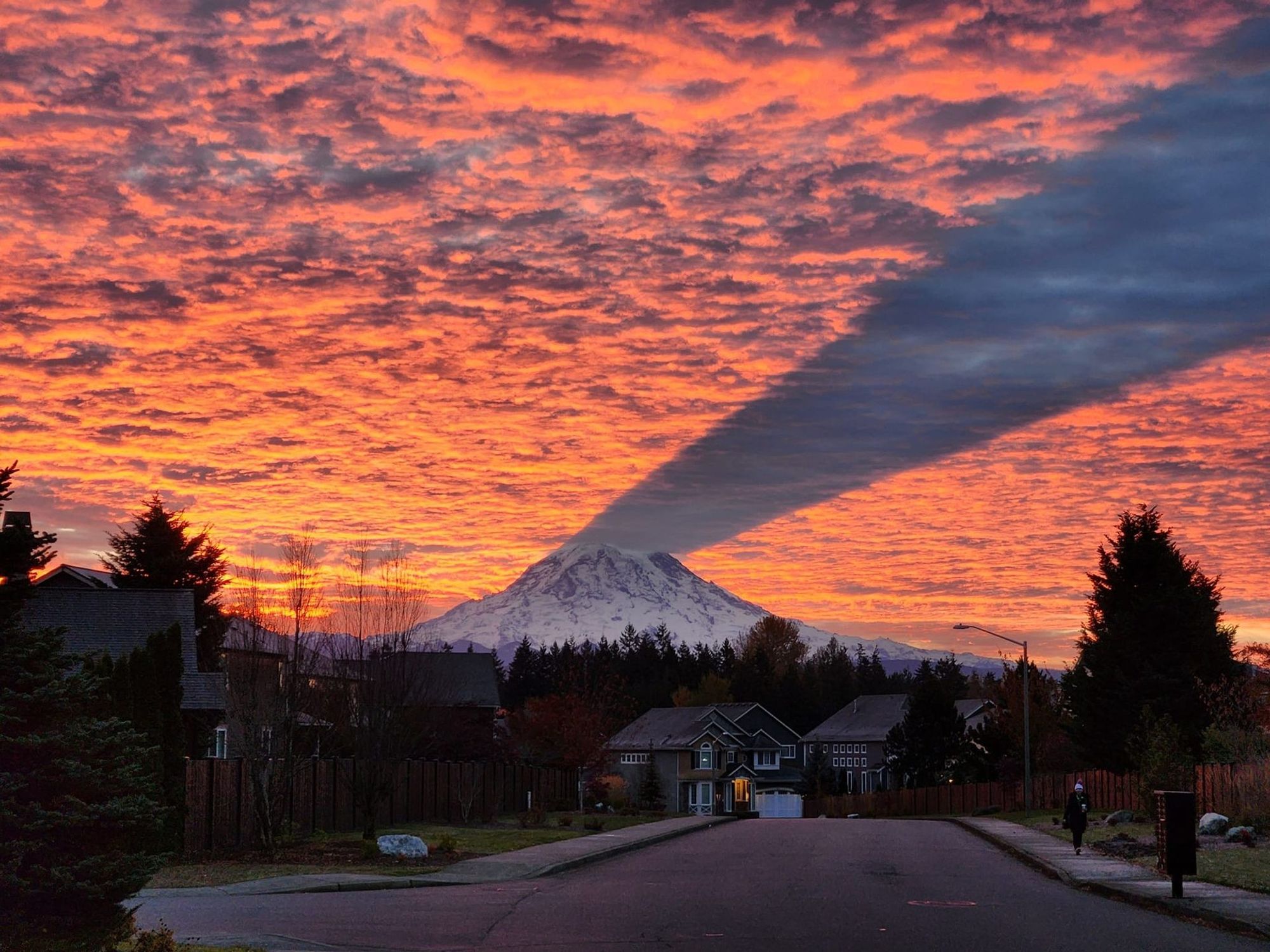 Mount Rainier casting a shadow on clouds from below during a sunset.